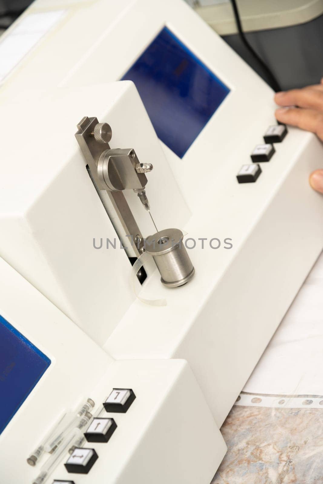 A vertical shot of a hand using a medical machine to test and manufacture pharmaceutical syringes by A_Karim