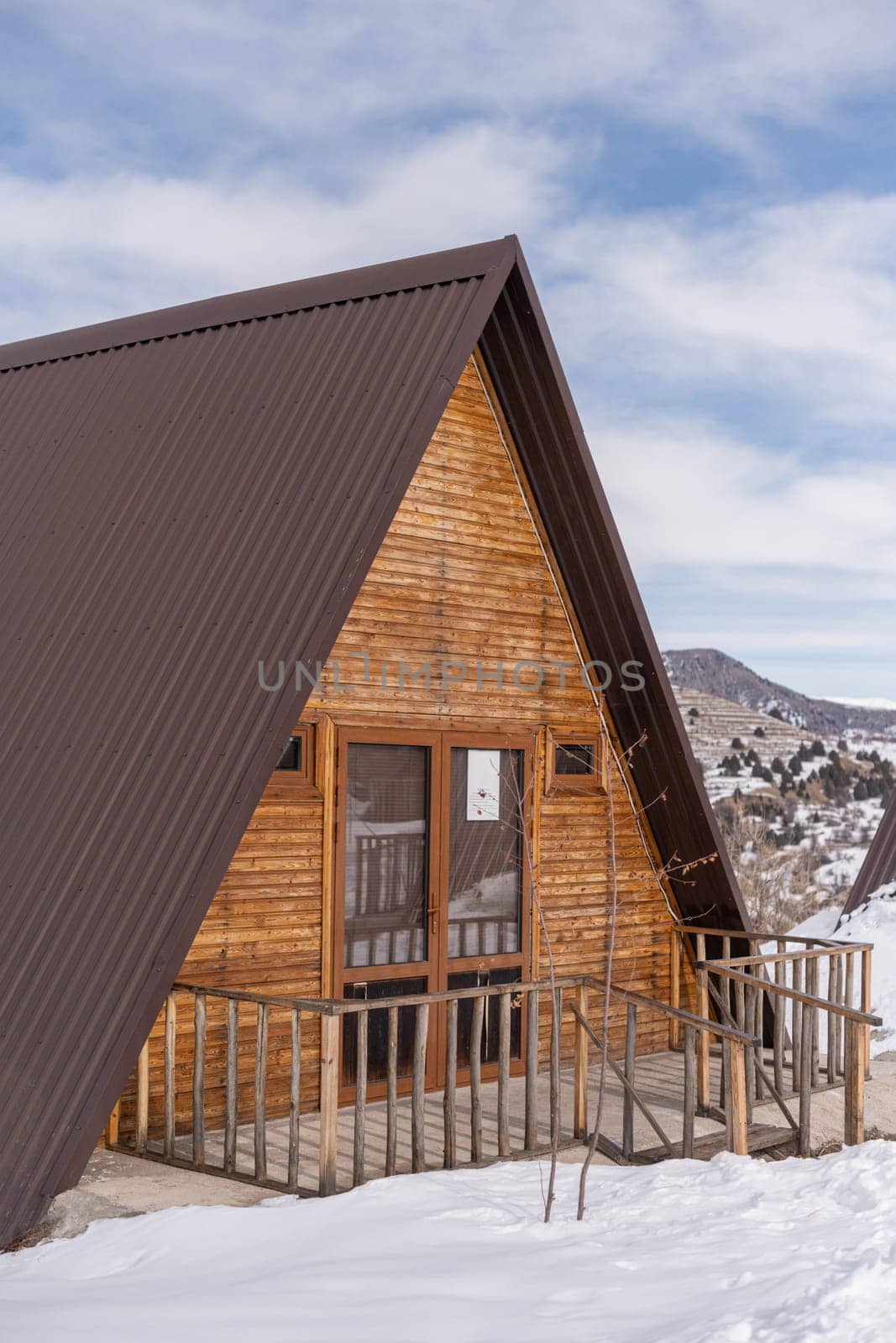 A vertical shot of a wooden cottage surrounded by snow. A recreation area in the mountains by A_Karim