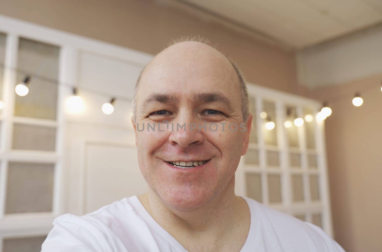 Smiling male blogger taking a selfie or video call from his apartment.