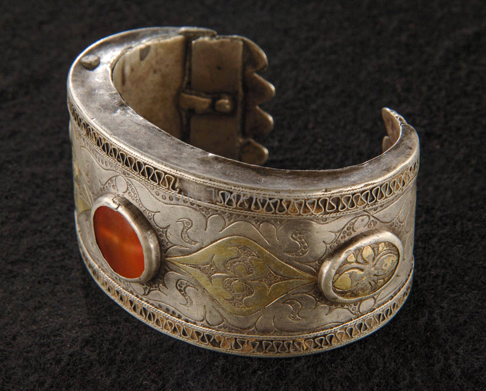 An antique bracelet with engraving and precious stones isolated on a black background