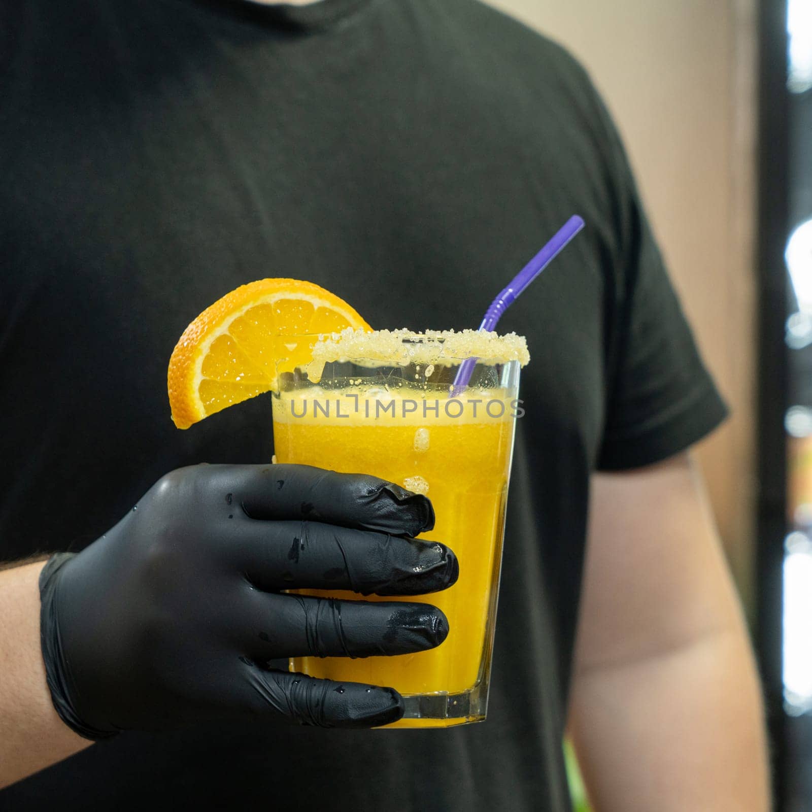 A vertical closeup of the bartender holding a glass of orange drink in the sports complex