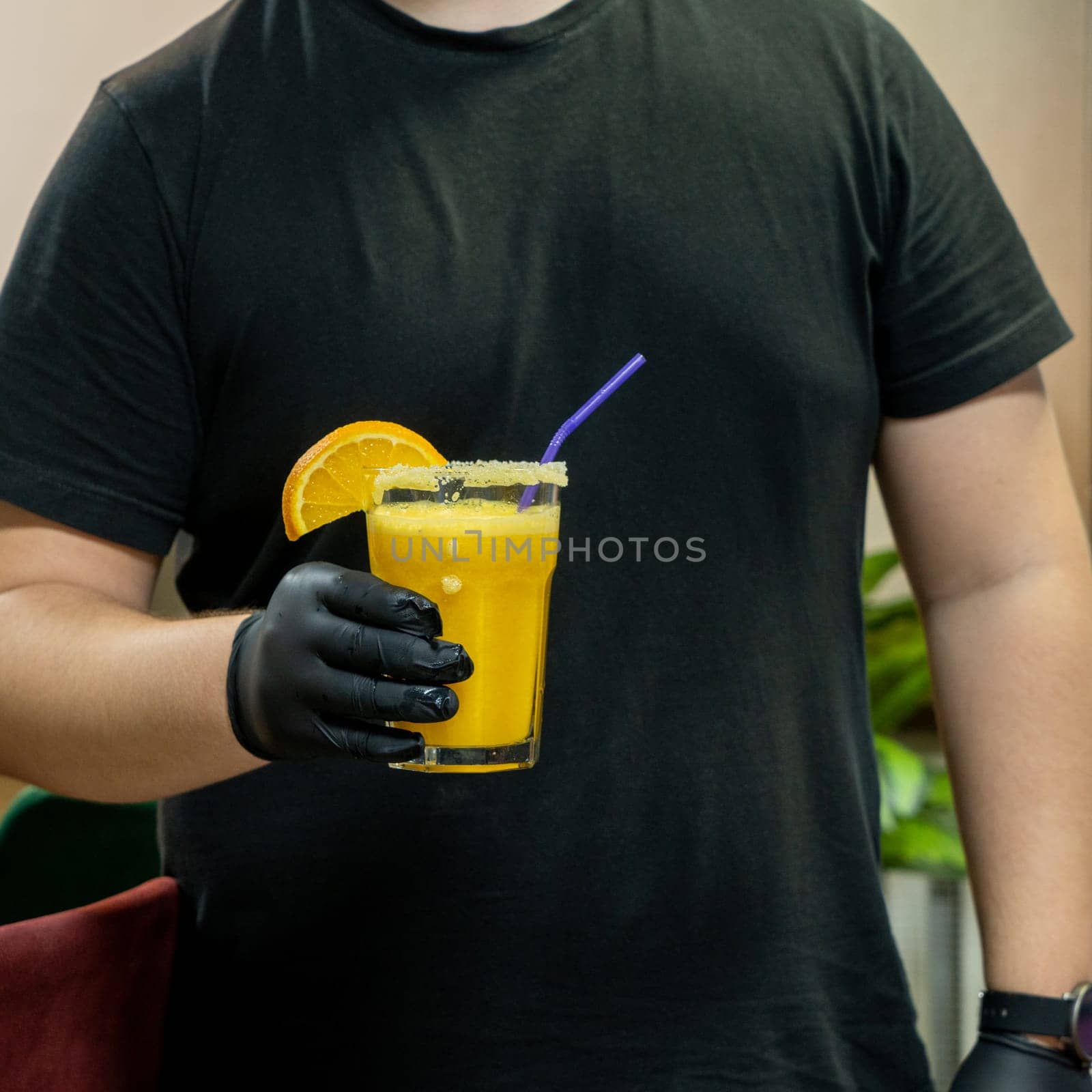 A vertical closeup of the bartender holding a glass of orange drink in the sports complex