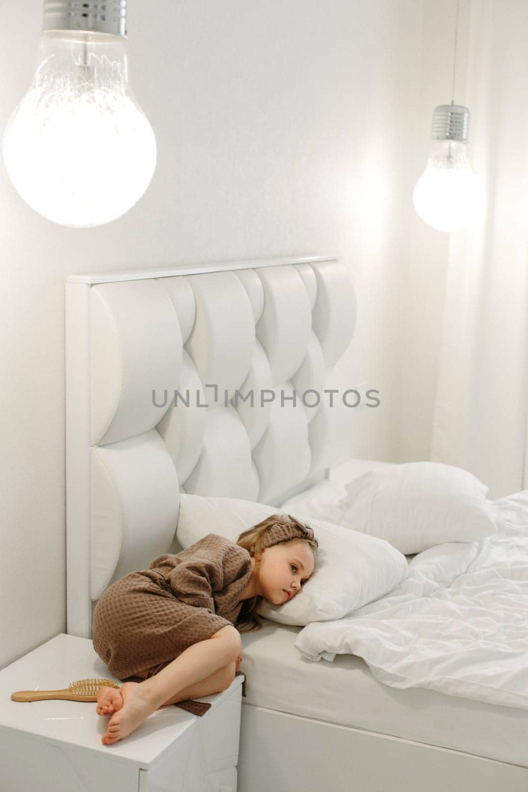 Portrait of a girl in a brown bathrobe, who lies on a nafa and a bed in a white bed.