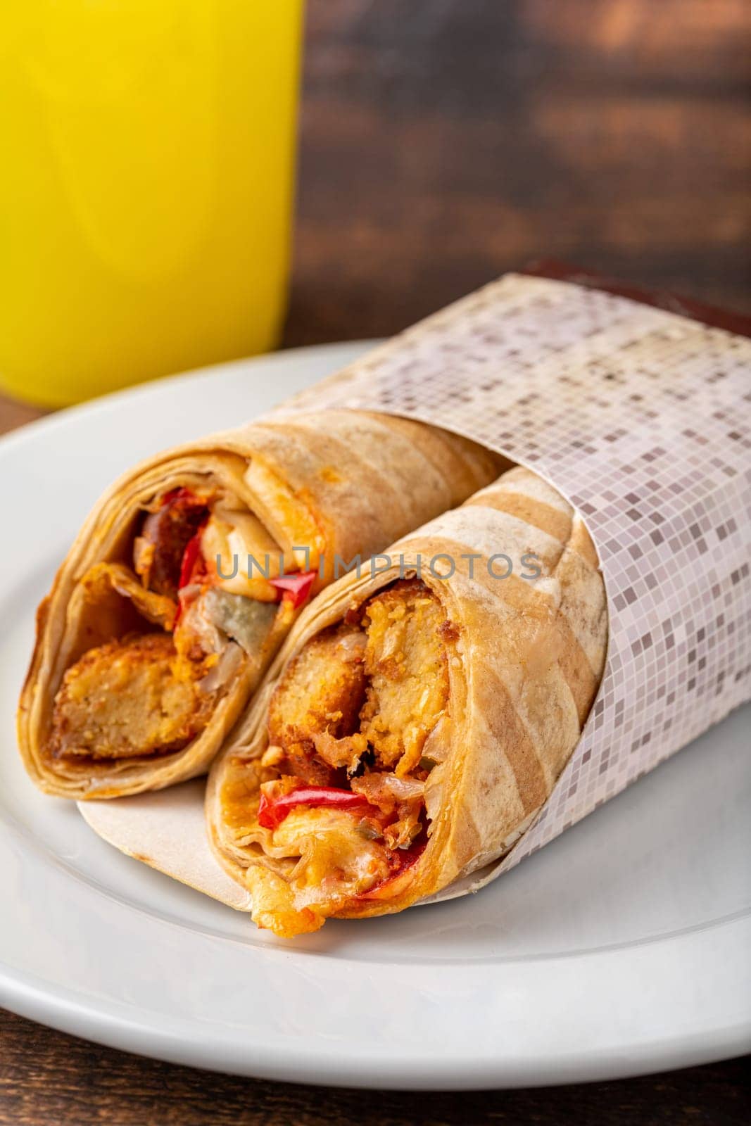 Chicken wrap with vegetables on a white porcelain plate on wooden table