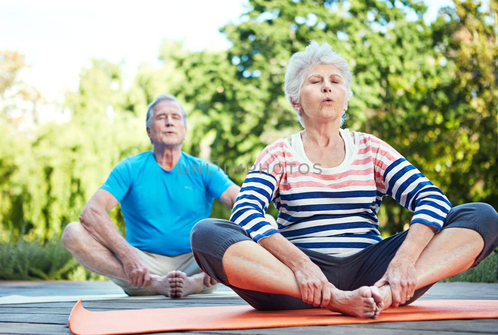 Find that zen. a senior couple doing yoga together outdoors. by YuriArcurs