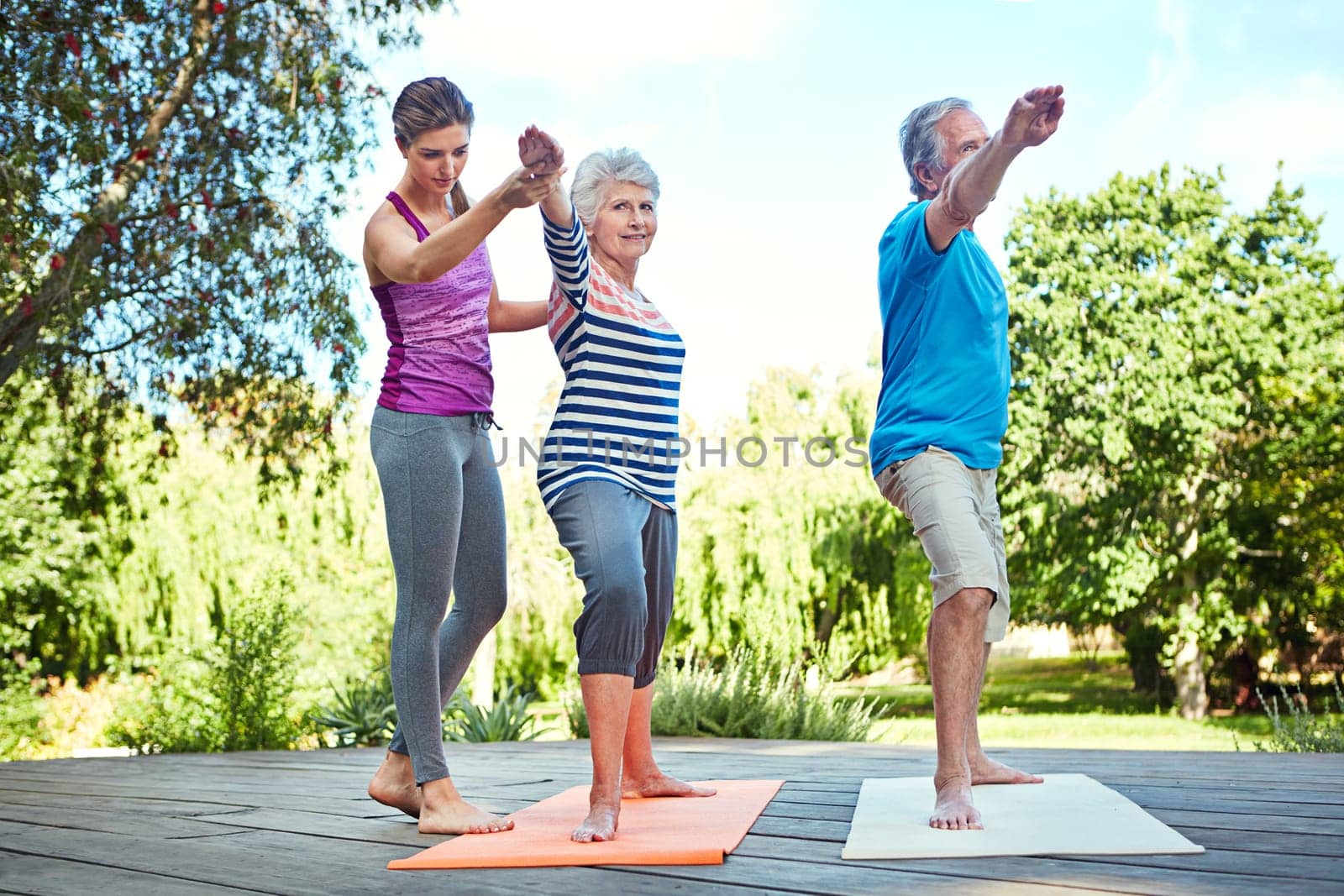 Stay fit in your senior years. a yoga instructor guiding a senior couple in a yoga class