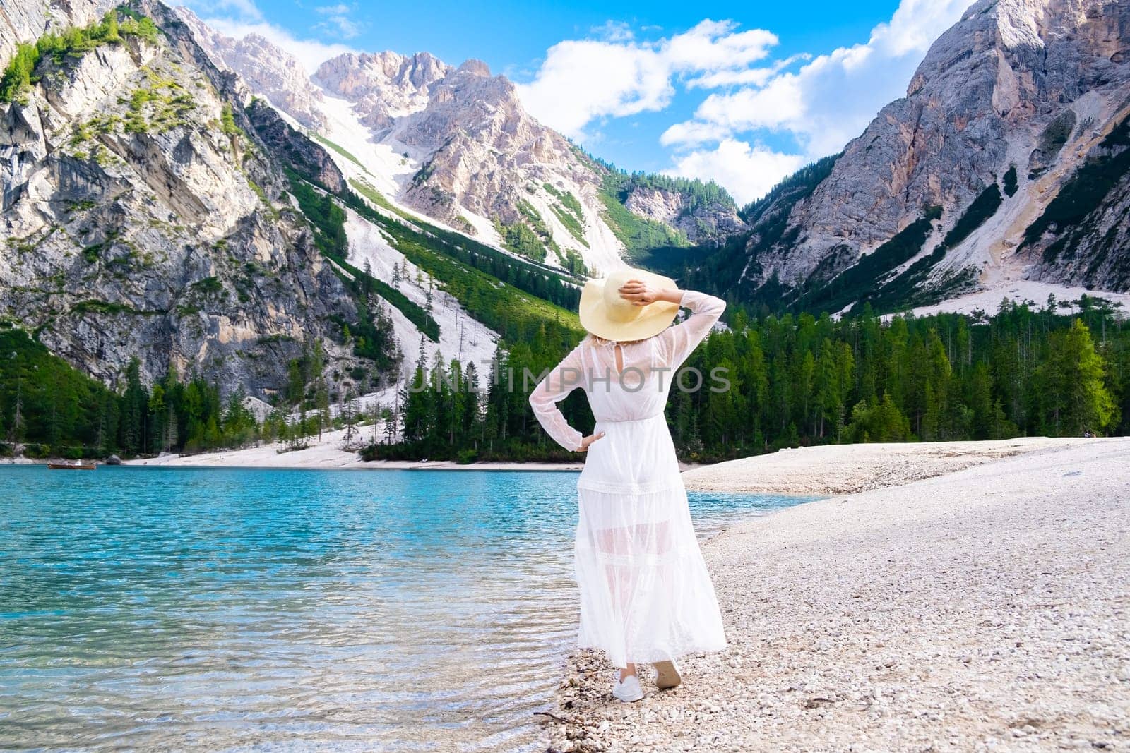 Beautiful woman relaxing and enjoying the view of Dolomites Alps and Lake Braies. Vacation concept.