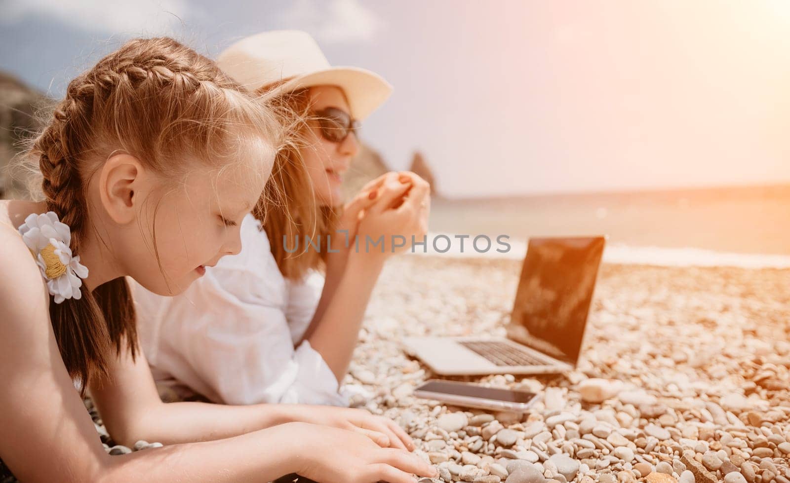 Woman sea laptop. Business woman with daughter, working on laptop by sea. Close up on hands of pretty lady typing on computer outdoors summer day. Freelance, digital nomad, travel and holidays concept by panophotograph