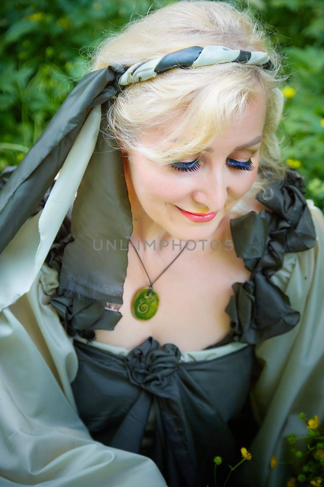 Adult mature woman 40-60 in a green long fairy dress in forest. Photo shoot in style of dryad and queen of nature. Fairy who loves nature in beautiful green summer forest. Concept of caring for nature by keleny