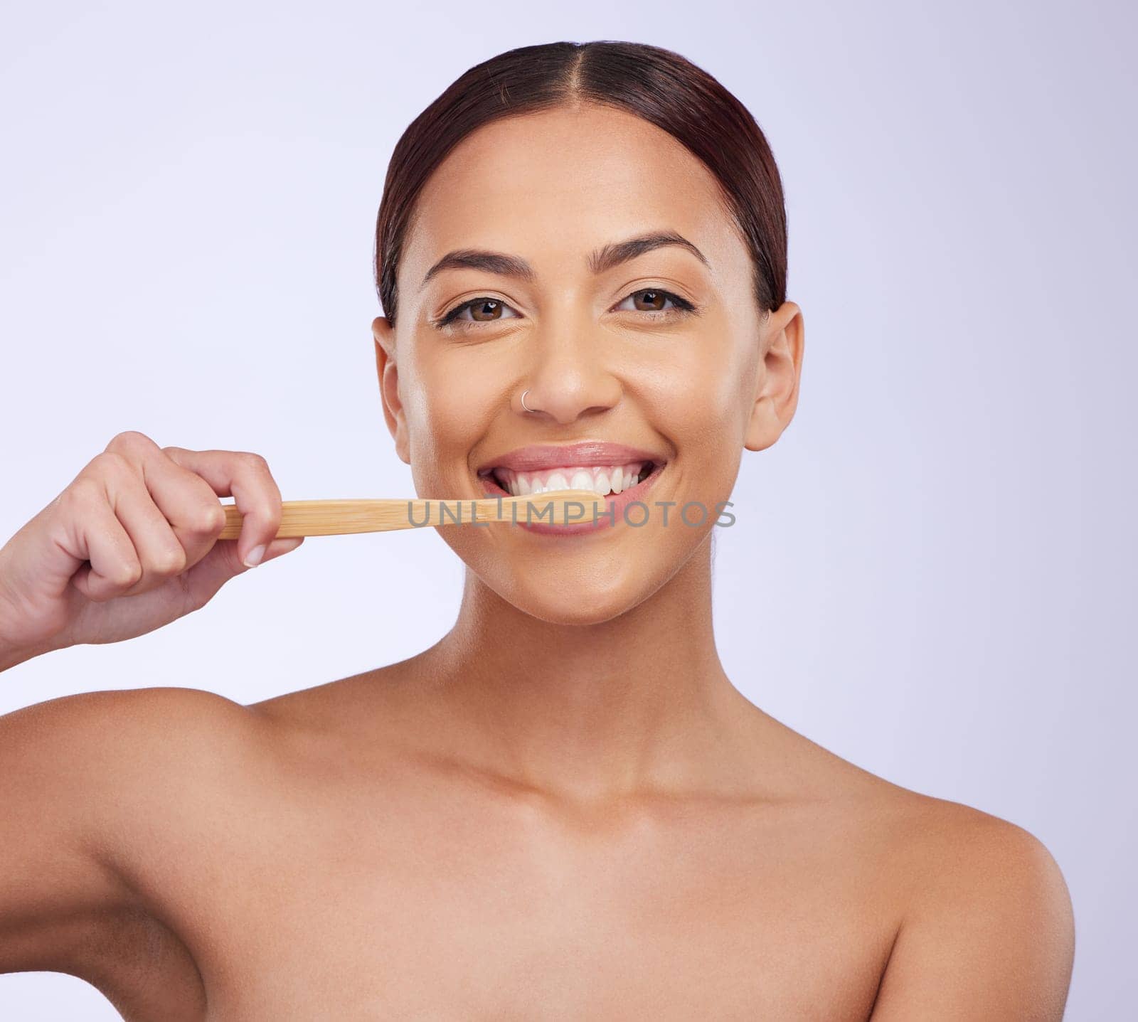 Portrait, dental or happy girl brushing teeth with smile for healthy oral hygiene in studio white background. Beauty or Brazilian woman model cleaning mouth with a natural bamboo wooden toothbrush.