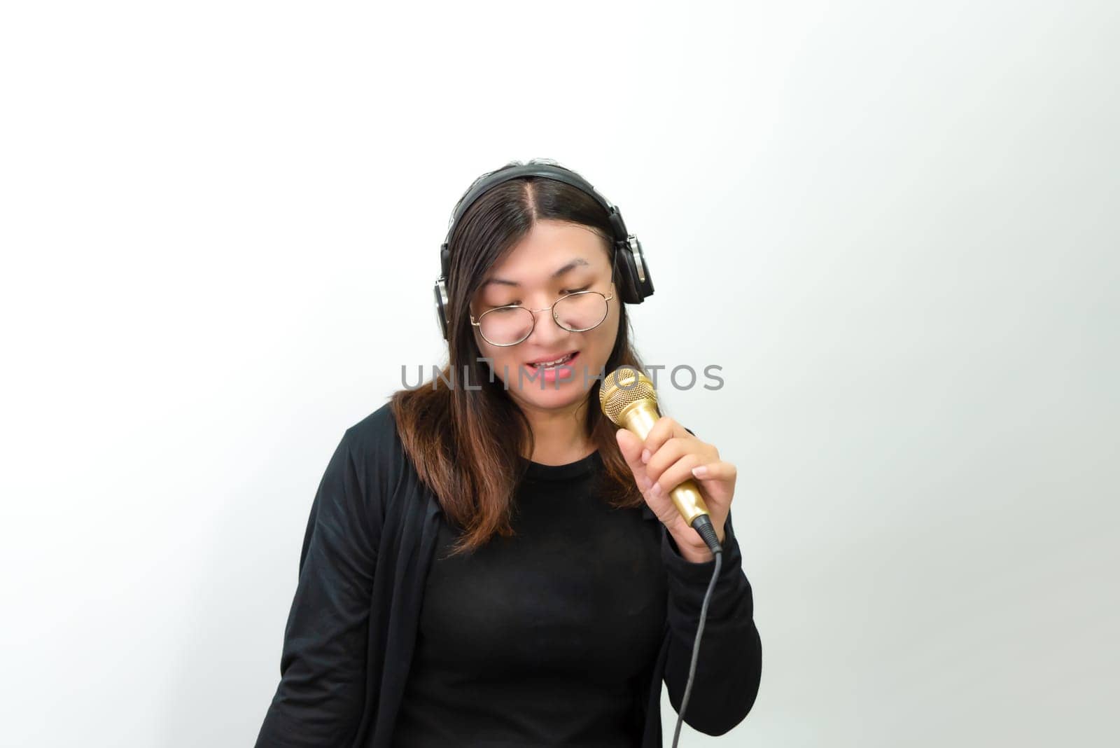 Beautiful asian woman (LGBTQ) is a singer. She enjoying sing a song or karaoke in music studio with microphone condenser and headphones for fun or voice creative