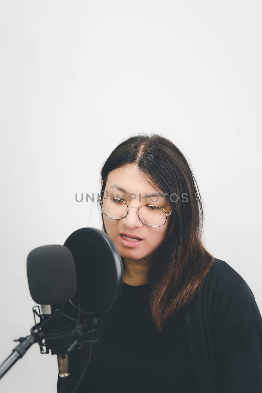 Beautiful asian woman (LGBTQ) is a singer. She enjoying sing a song or karaoke in music studio with microphone condenser and headphones for fun or voice creative