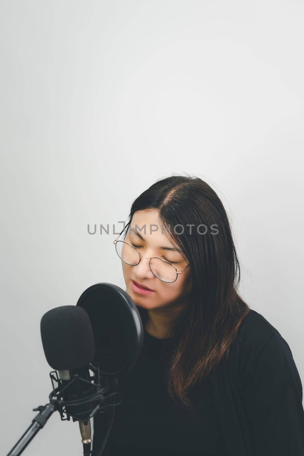 Beautiful asian woman (LGBTQ) is a singer. She enjoying sing a song or karaoke in music studio with microphone condenser and headphones for fun or voice creative