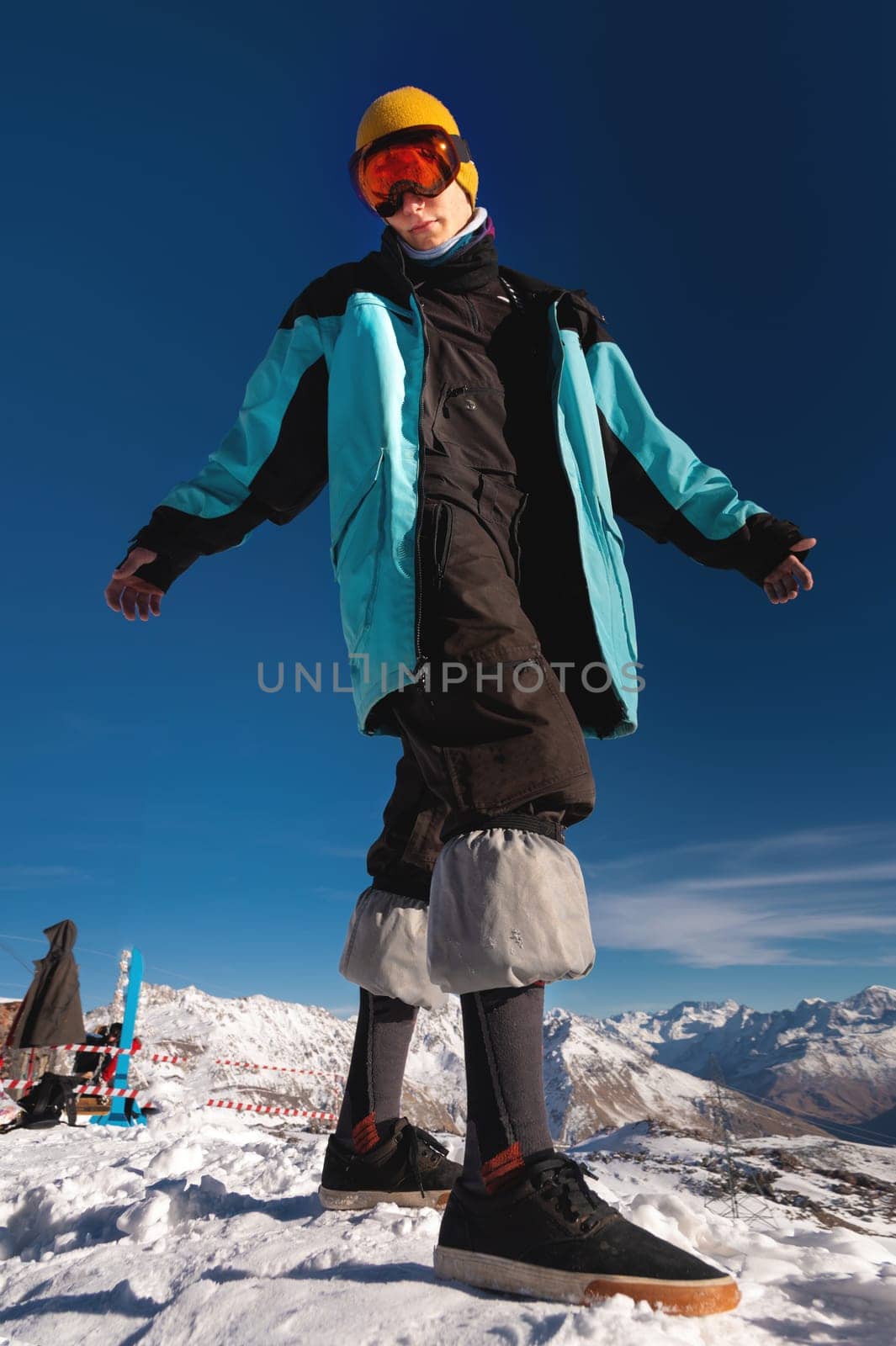 smiling attractive man in a warm windbreaker, hat, standing and looking at the camera, against the backdrop of snow-capped mountains. The concept of the cold winter season by yanik88