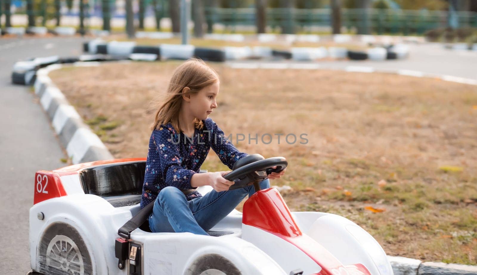 Little girl driving car on kids road in adventure park