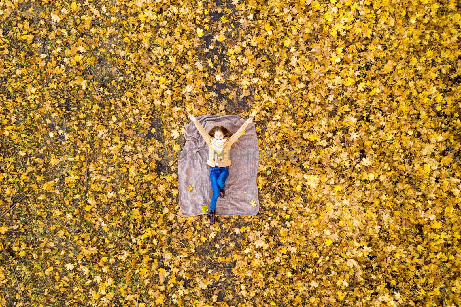 Overviewed school girl lying on carpet of leaves