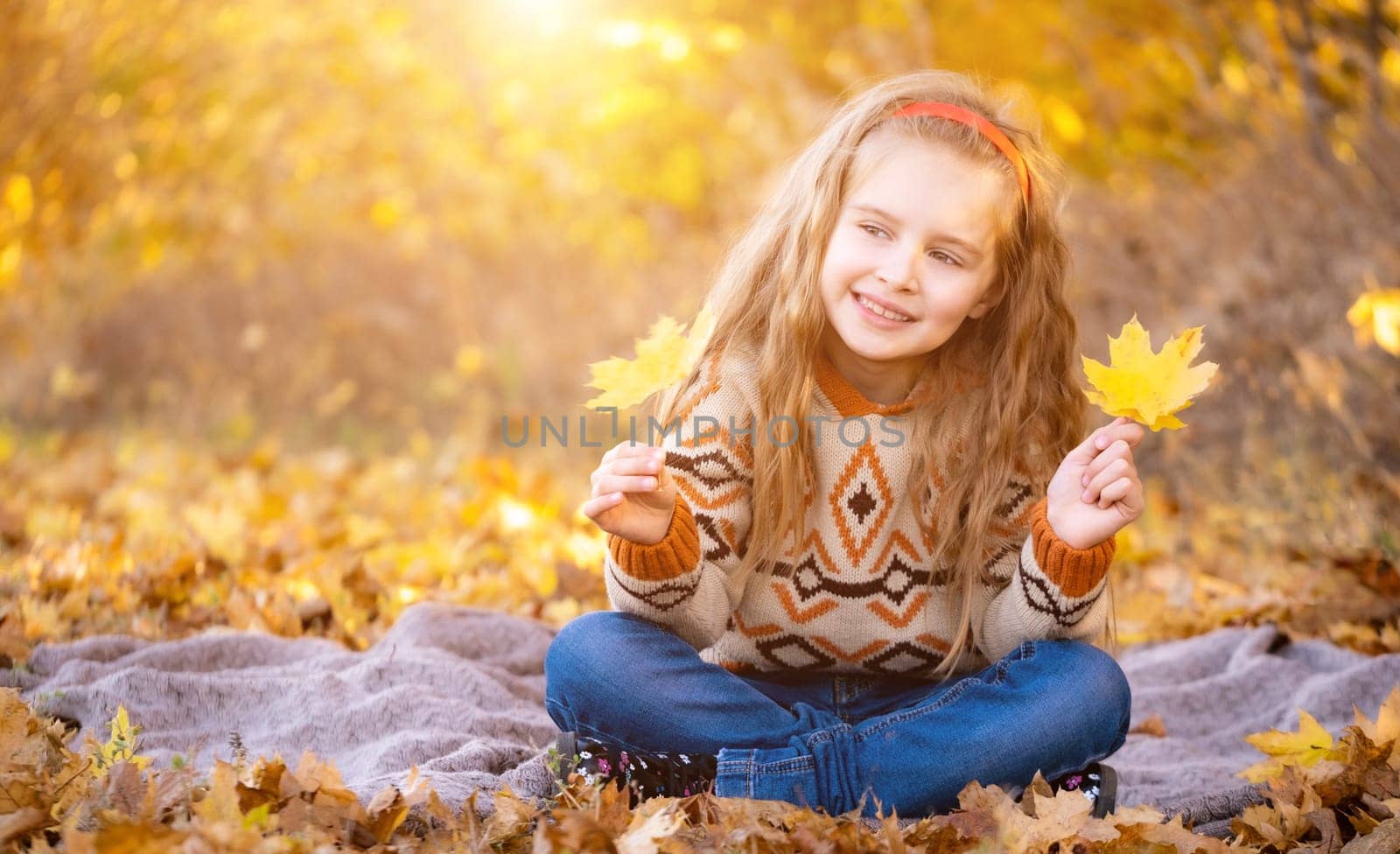 Cute little girl holding yellow leaves outdoors
