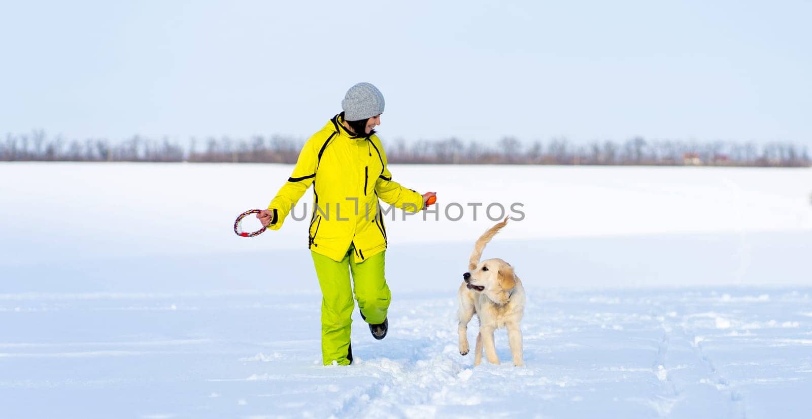 Girl with cute young retriever dog on winter walk