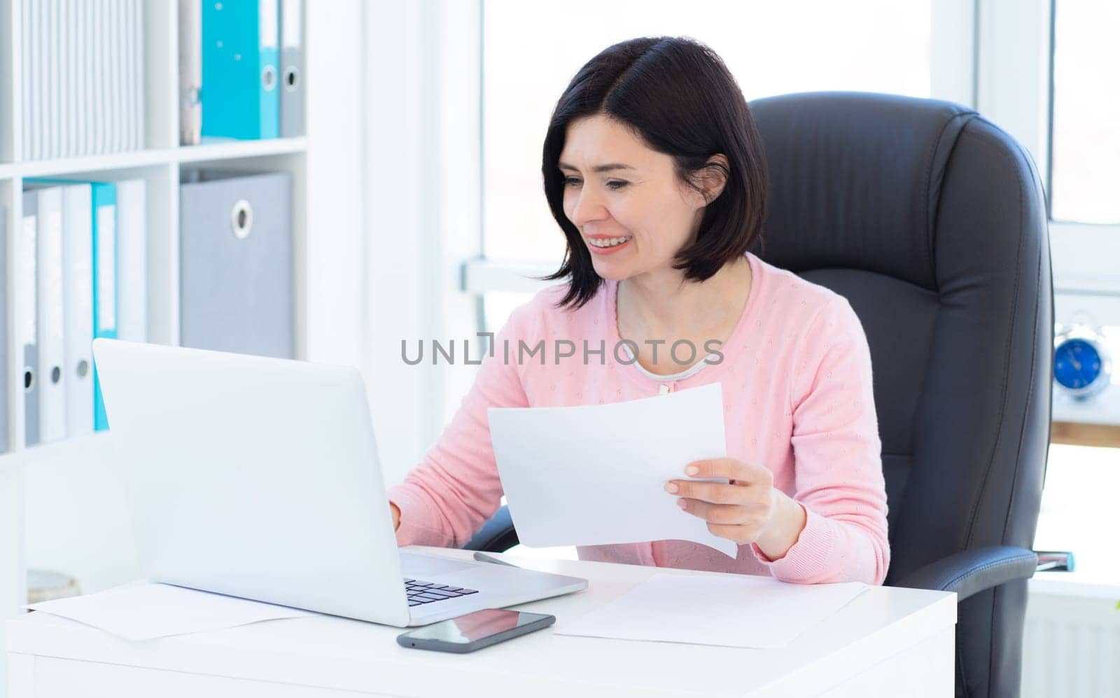Stylish woman working on laptop in light office