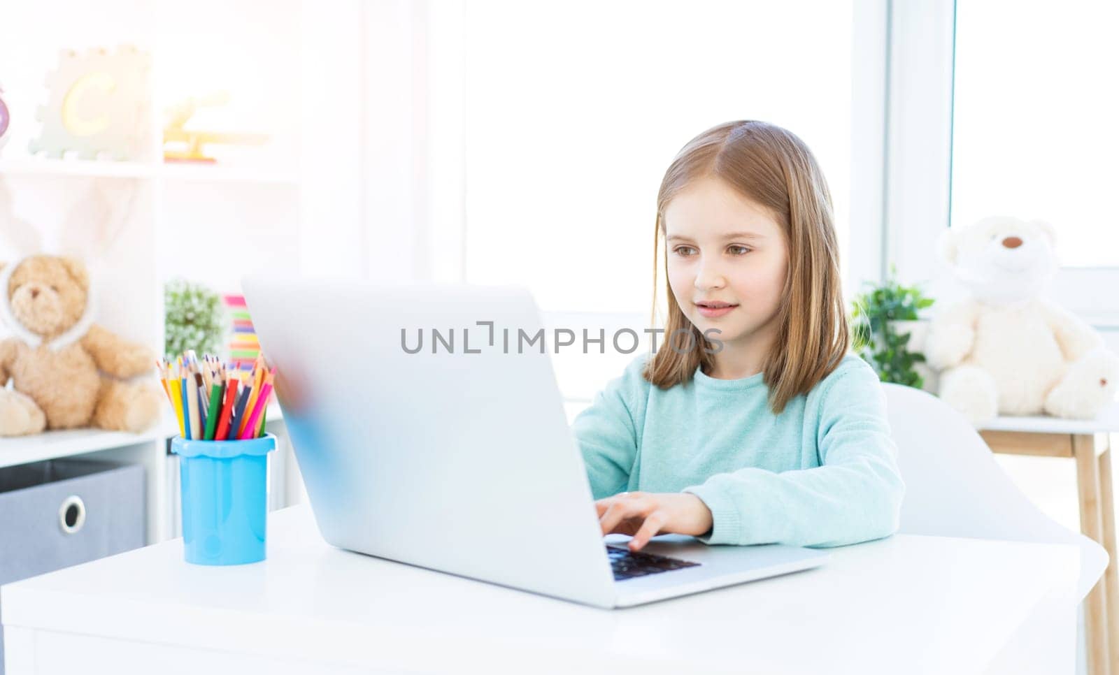 Beautiful little girl working on laptop at home