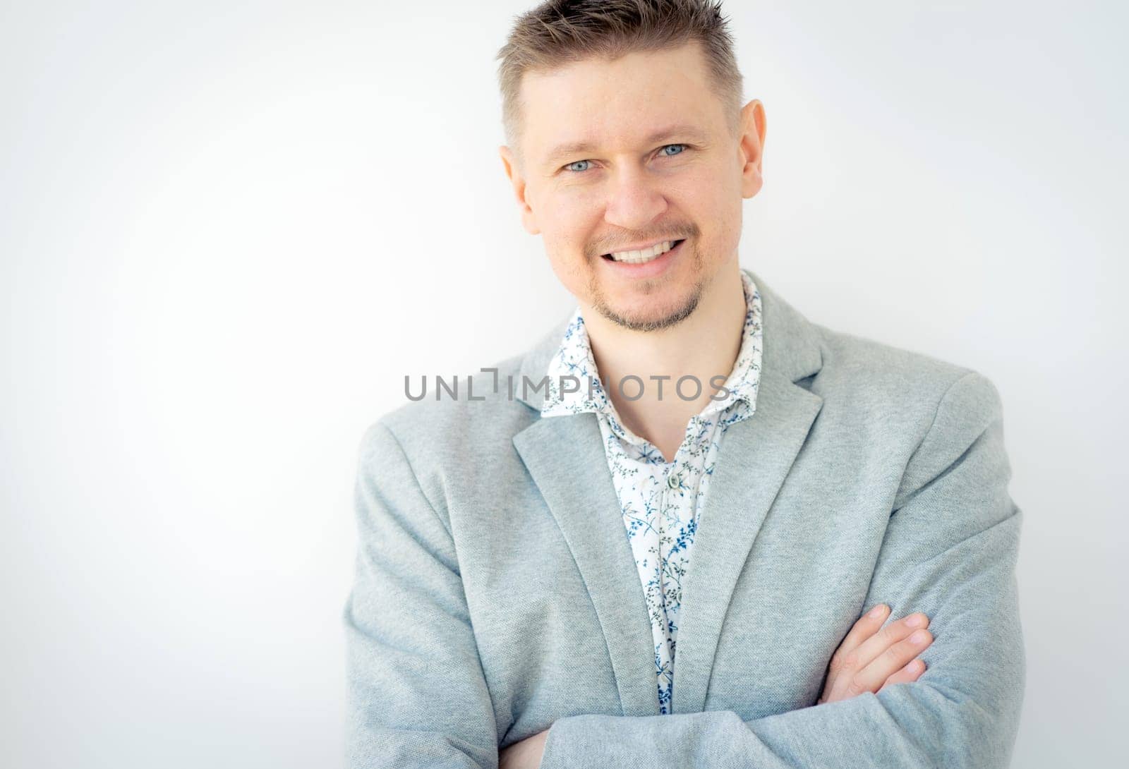 Portrait of smiling young man in gray jacket isolated on white background