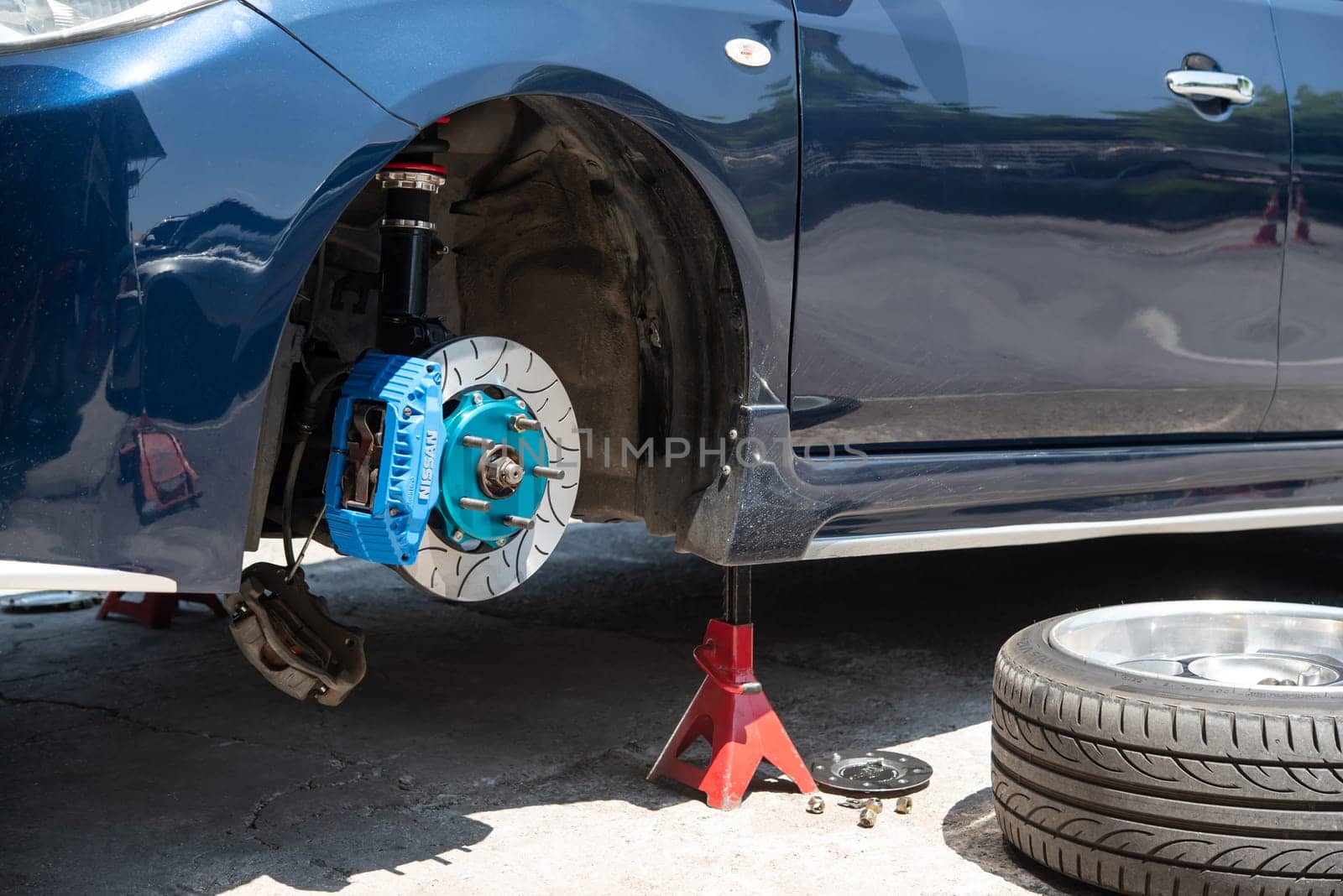 Bangkok, Thailand - March 6, 2021 : Unidentified car mechanic or serviceman disassembly and checking a disc brake and asbestos brake pads for fix and repair problem at car garage or repair shop