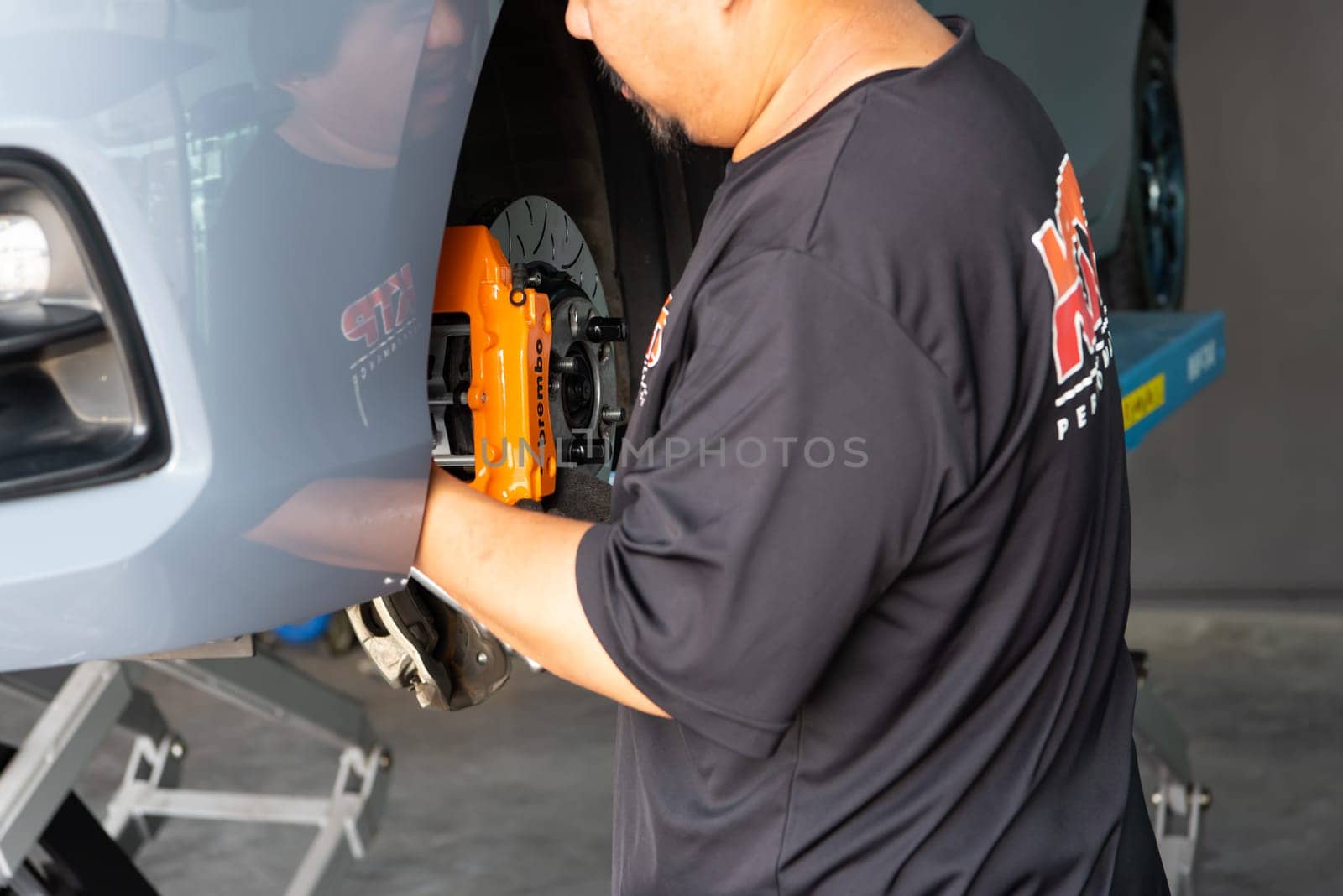 Bangkok, Thailand - February 4, 2023 : Unidentified car mechanic or serviceman disassembly and checking a disc brake and asbestos brake pads for fix and repair problem at car garage or repair shop
