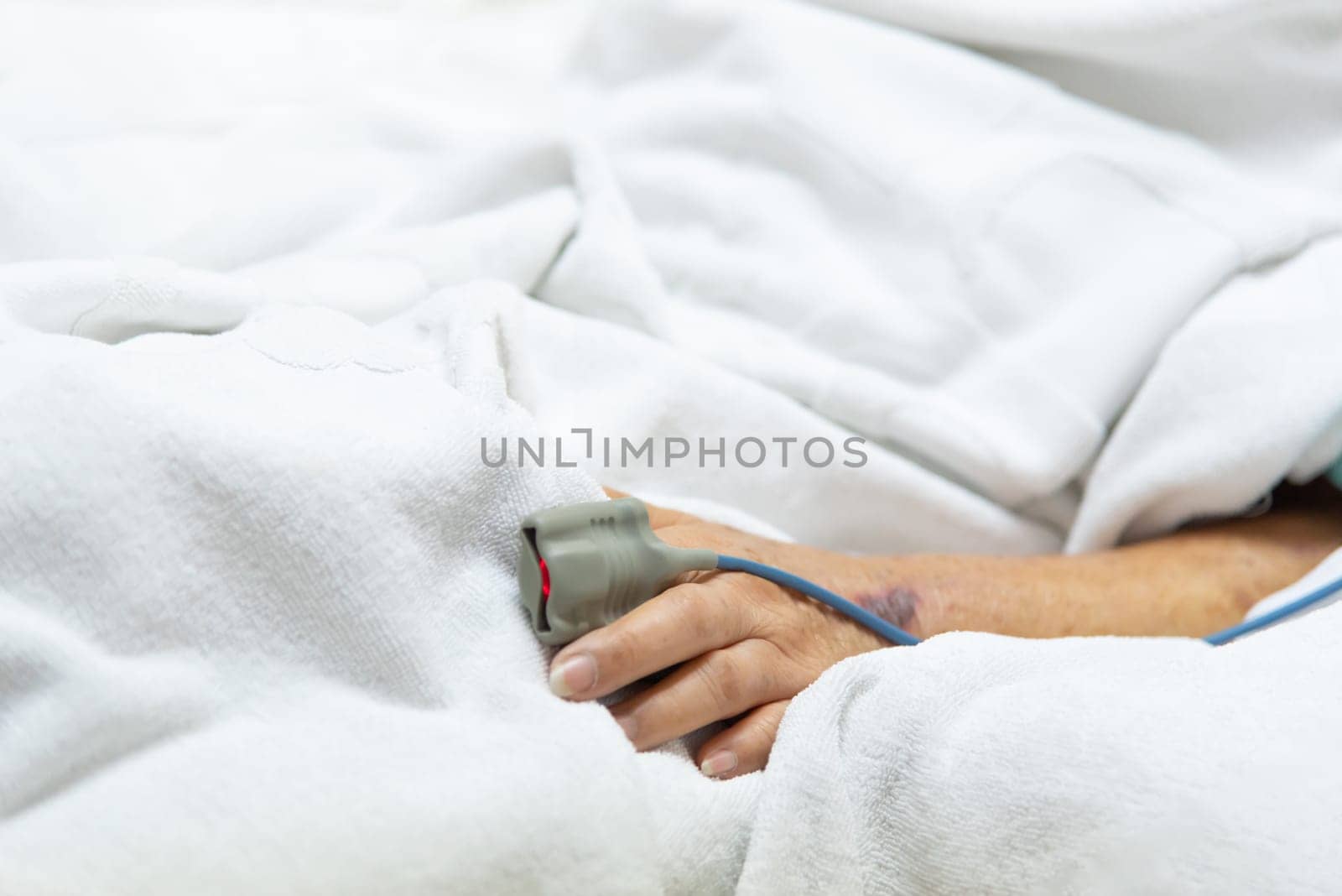 Patient asian elder woman 80s flu covid19 with pulse gauge for heartbeat measuring and blood pressure on a patient elderly finger on patient bed in intensive care unit (ICU.) room at hospital