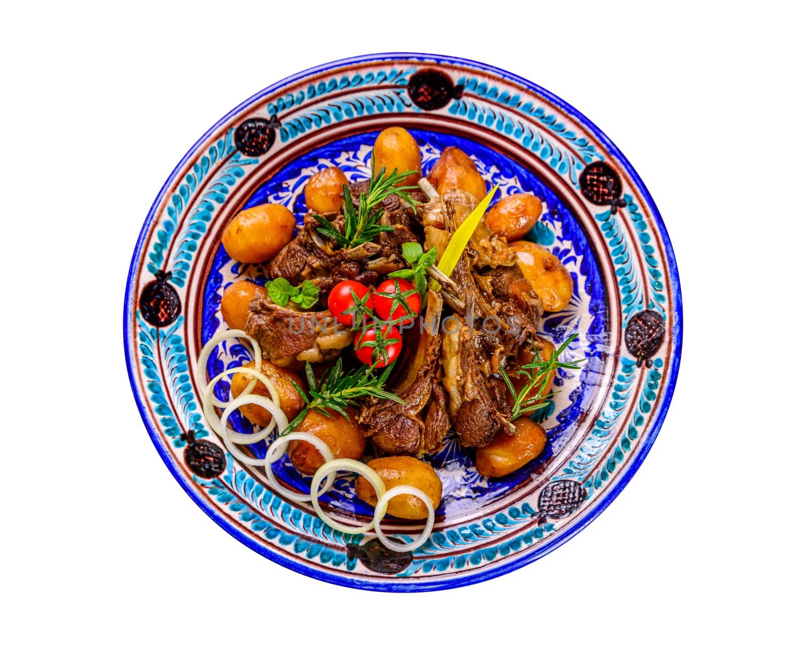 A top view of a national Uzbek dish with meat and potatoes served in a plate with traditional patterns