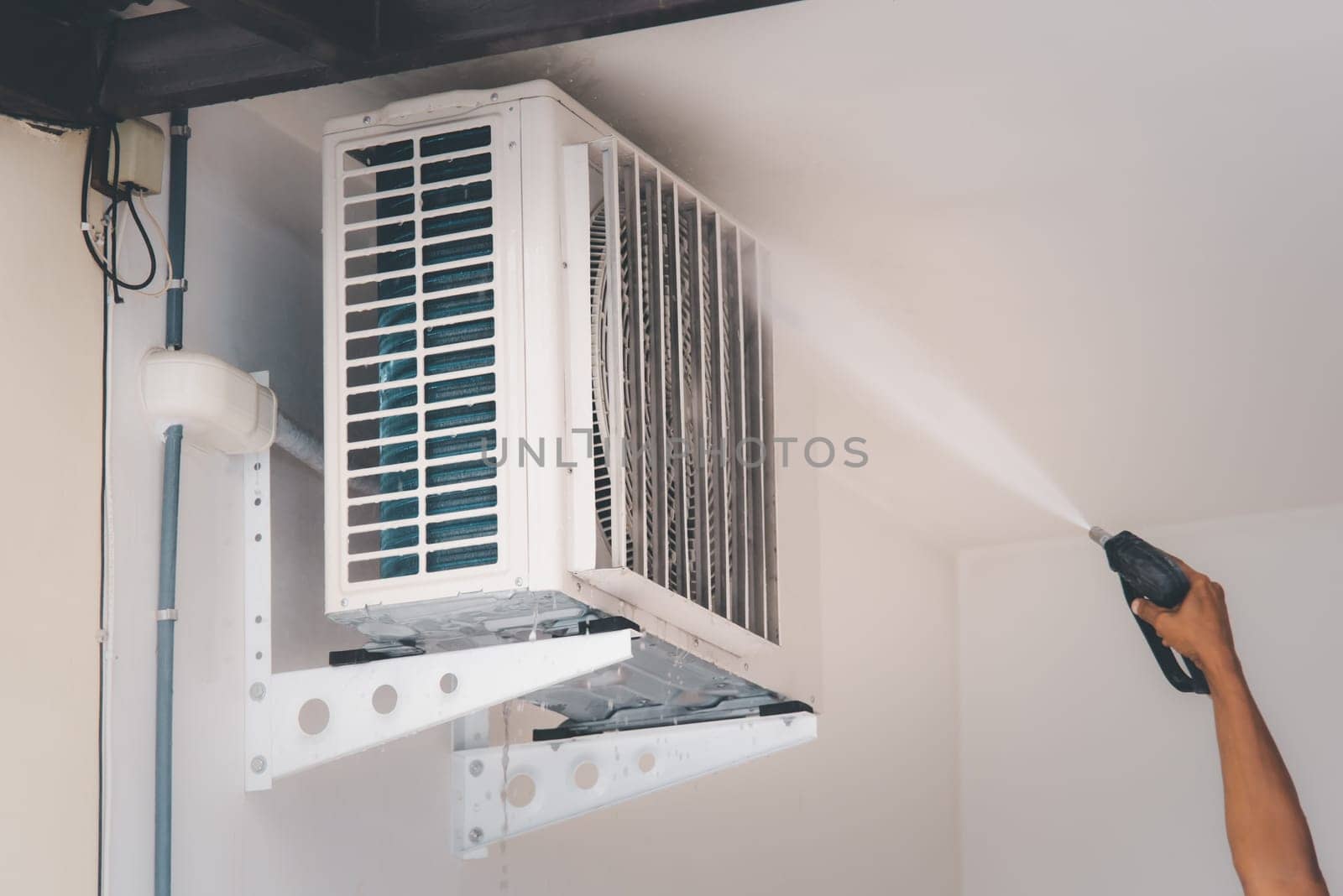 Worker to cleaning coil cooler of air conditioner by water for clean a dust on the wall in customer home when maintenance service