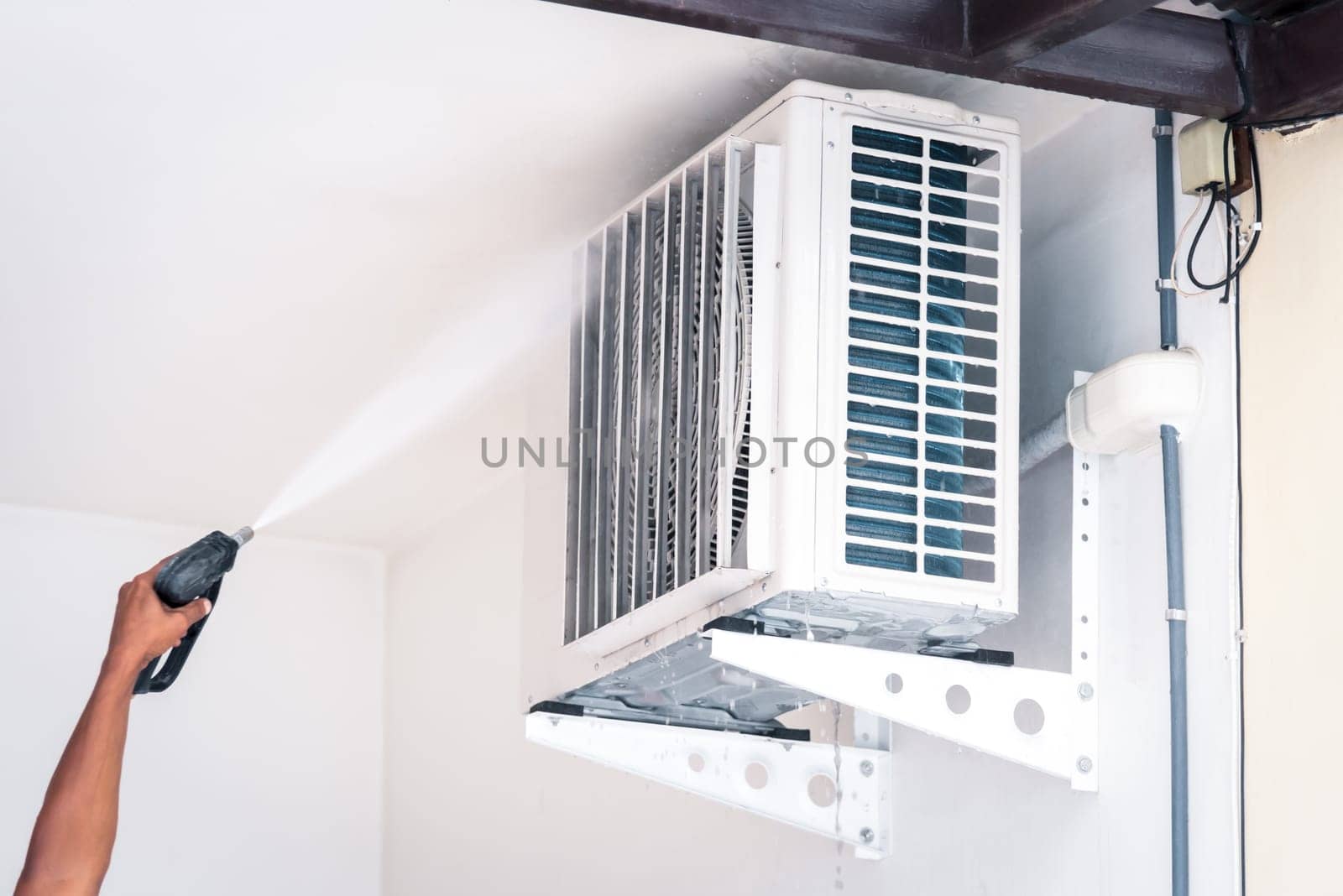 Worker to cleaning coil cooler of air conditioner by water for clean a dust on the wall in customer home when maintenance service