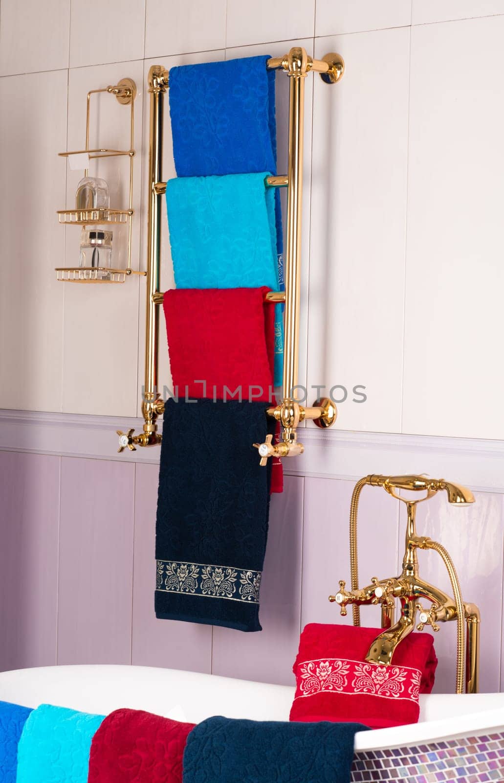 A vertical shot of colorful bamboo towels hanging on a golden rack in a bathroom by A_Karim