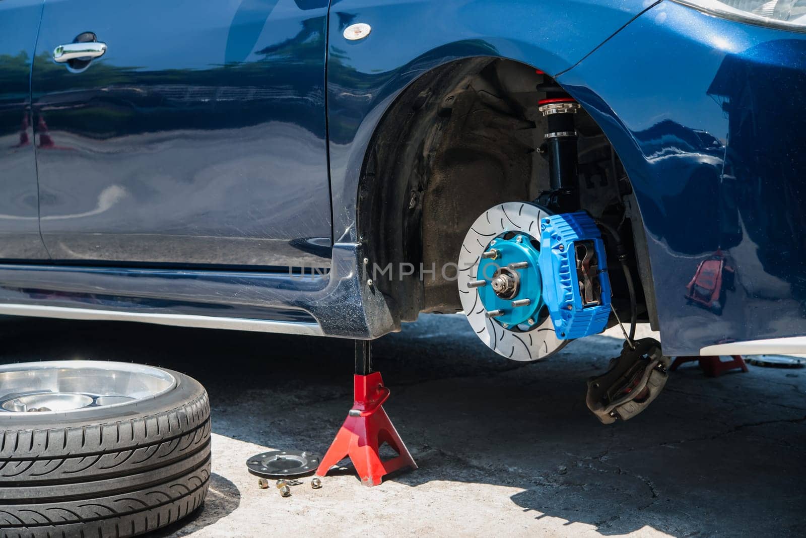 Car mechanic or serviceman disassembly and checking a disc brake and asbestos brake pads for fix and repair problem at car garage or repair shop