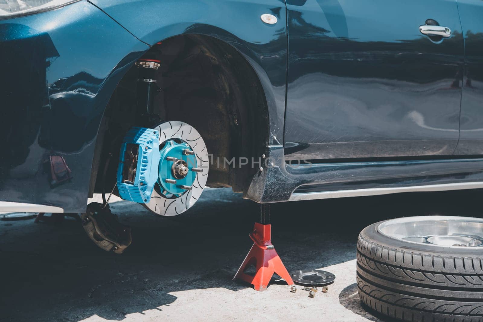 Car mechanic or serviceman disassembly and checking a disc brake and asbestos brake pads for fix and repair problem at car garage or repair shop