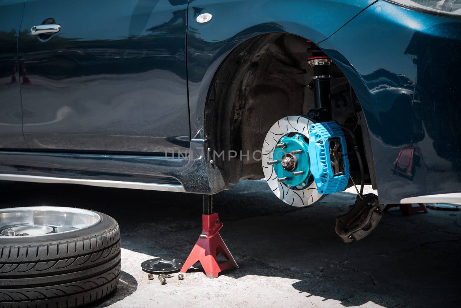 Car mechanic or serviceman disassembly and checking a disc brake and asbestos brake pads for fix and repair problem at car garage or repair shop