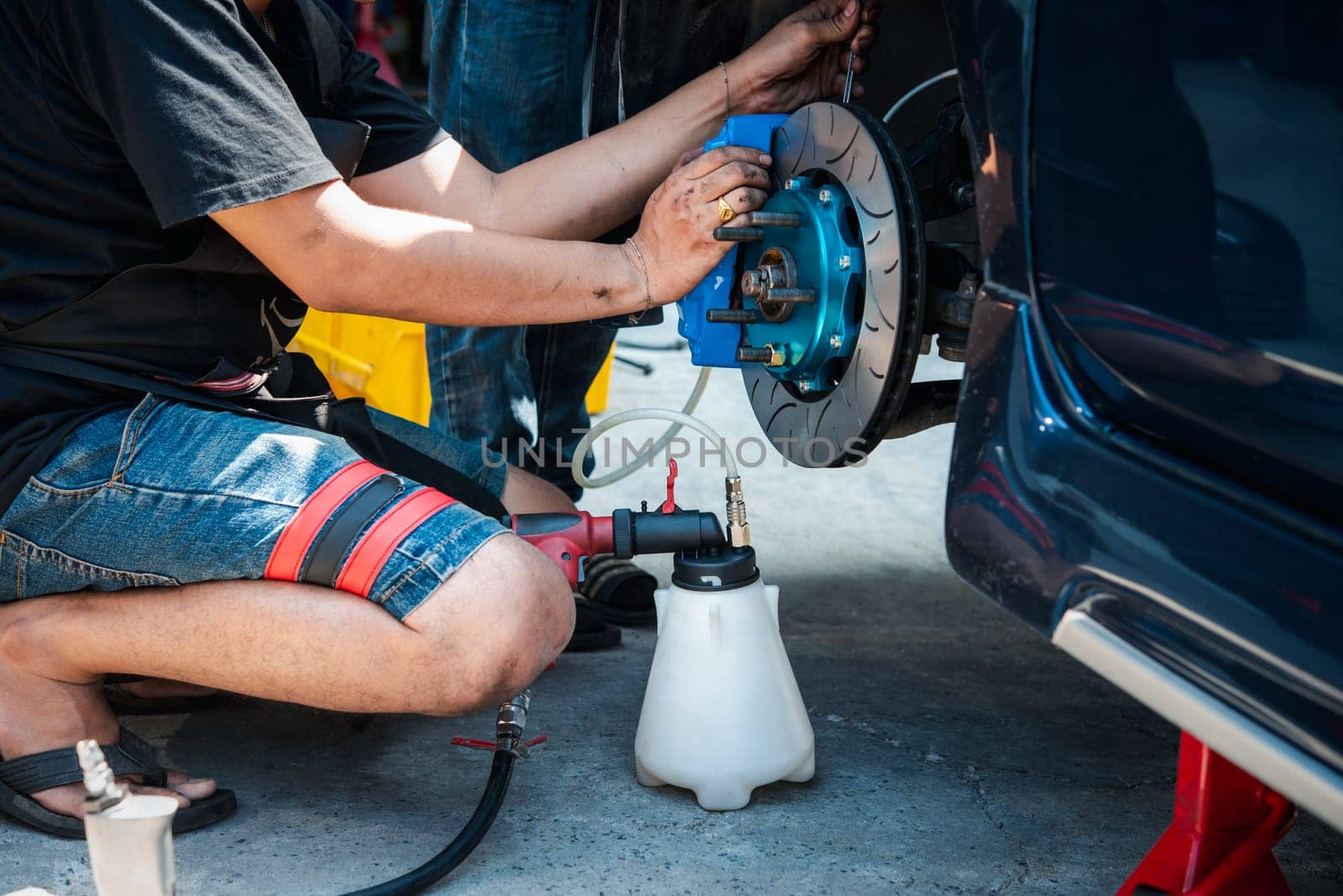 Bangkok, Thailand - March 6, 2021 : Unidentified car mechanic or serviceman disassembly and checking a disc brake and asbestos brake pads for fix and repair problem at car garage or repair shop