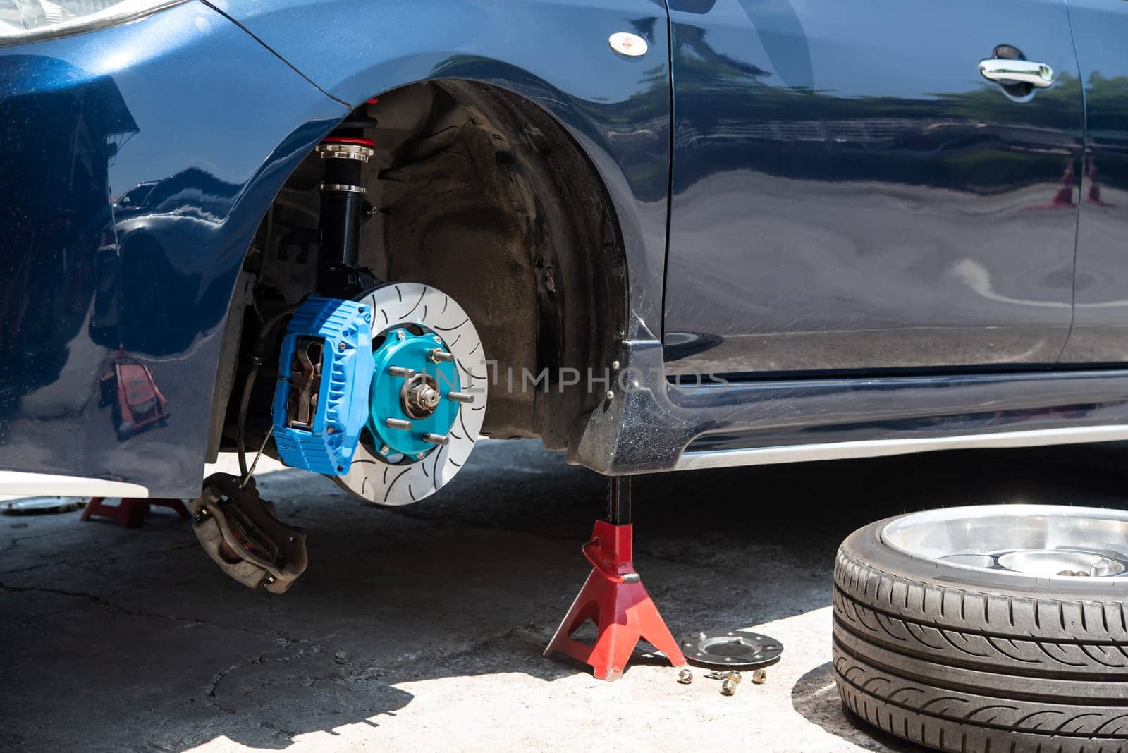 Car mechanic or serviceman disassembly and checking a disc brake and asbestos brake pads for fix and repair problem at car garage or repair shop