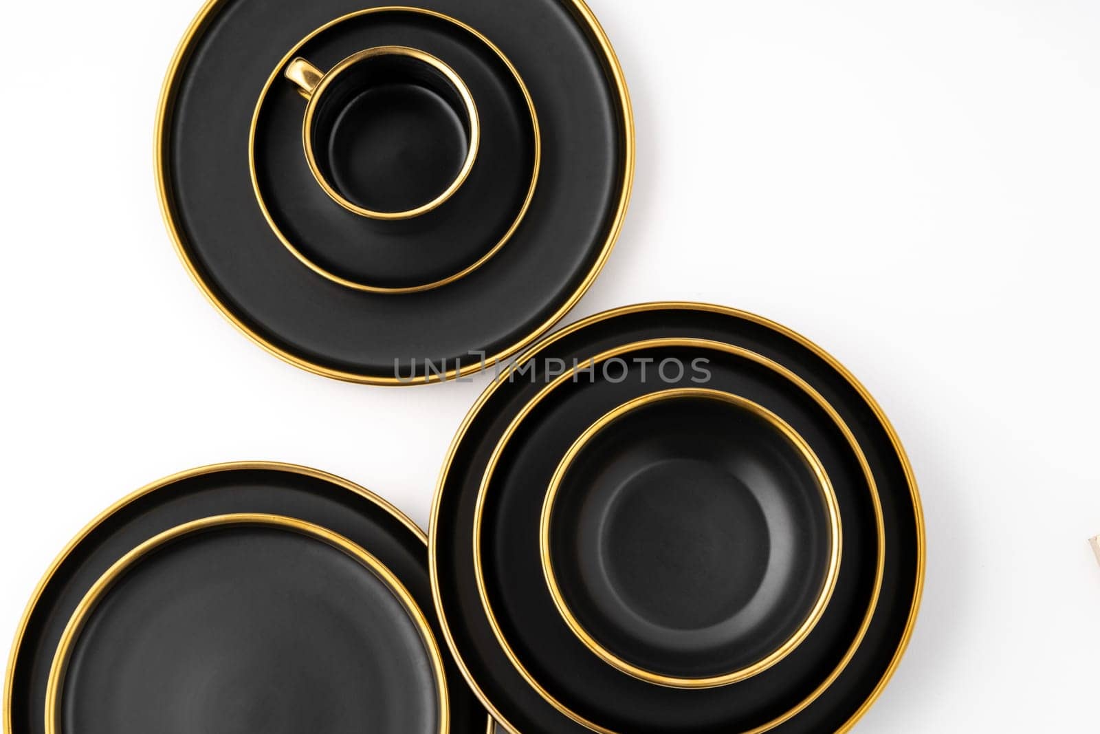 A set of black and golden ceramic plates and cup on a white background Top view by A_Karim