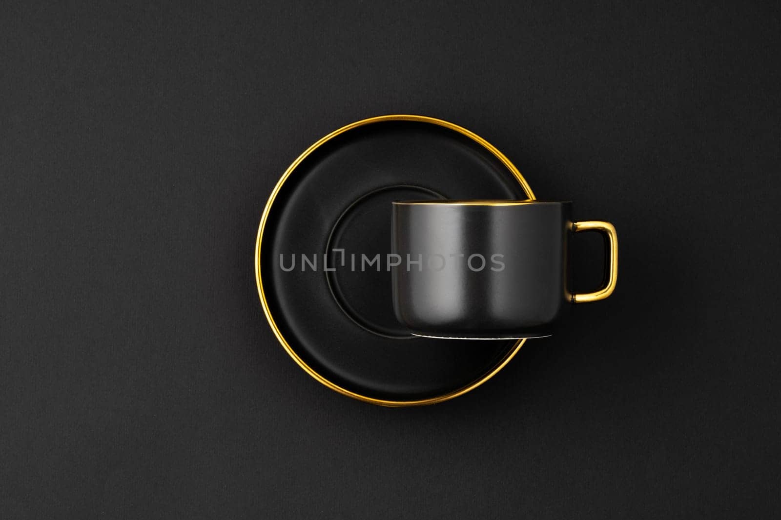 A set of black and golden ceramic plates and cup on a black background. Top view by A_Karim