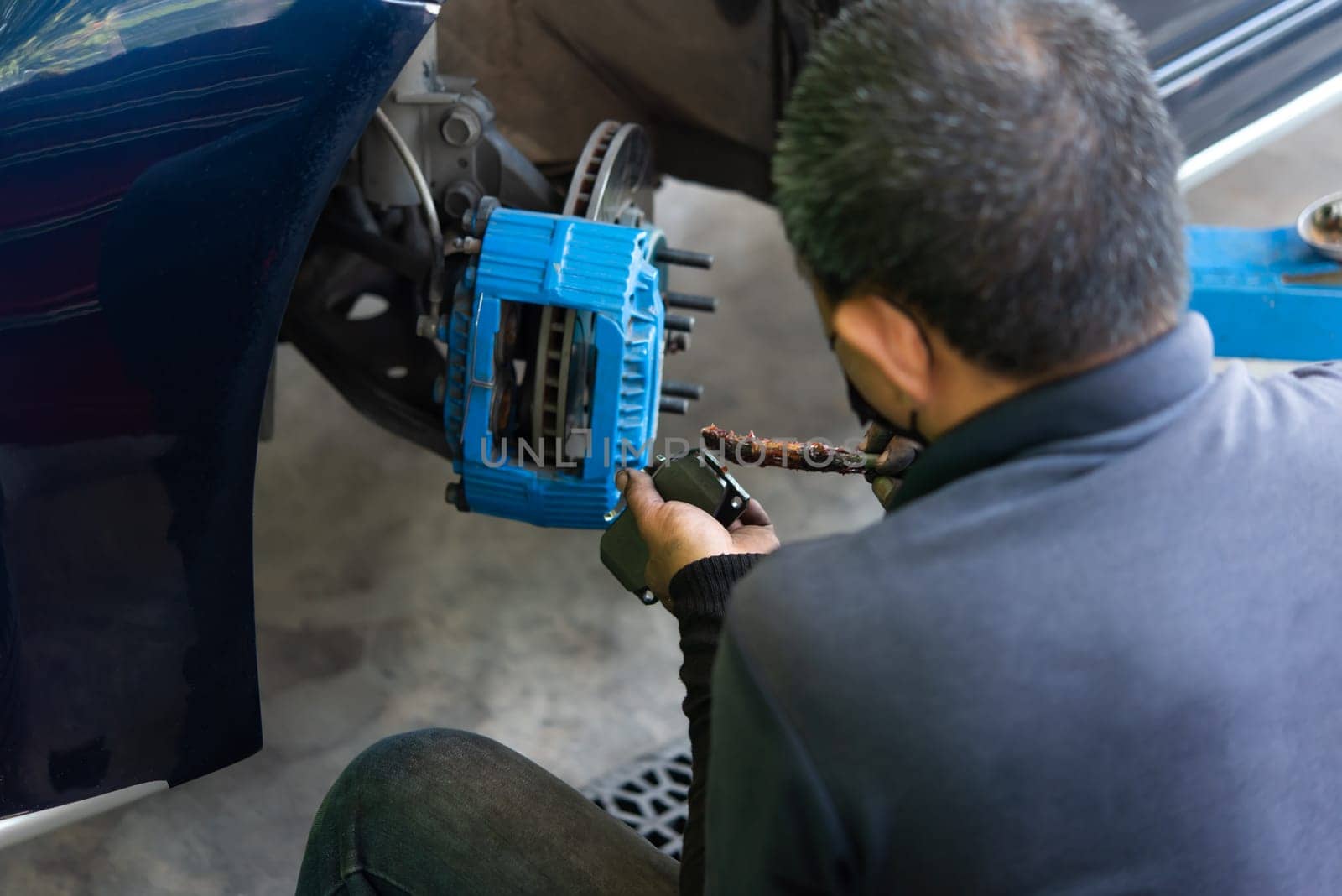 Bangkok, Thailand - January 16, 2022 : Unidentified car mechanic or serviceman disassembly and checking a disc brake and asbestos brake pads for fix and repair problem at car garage or repair shop