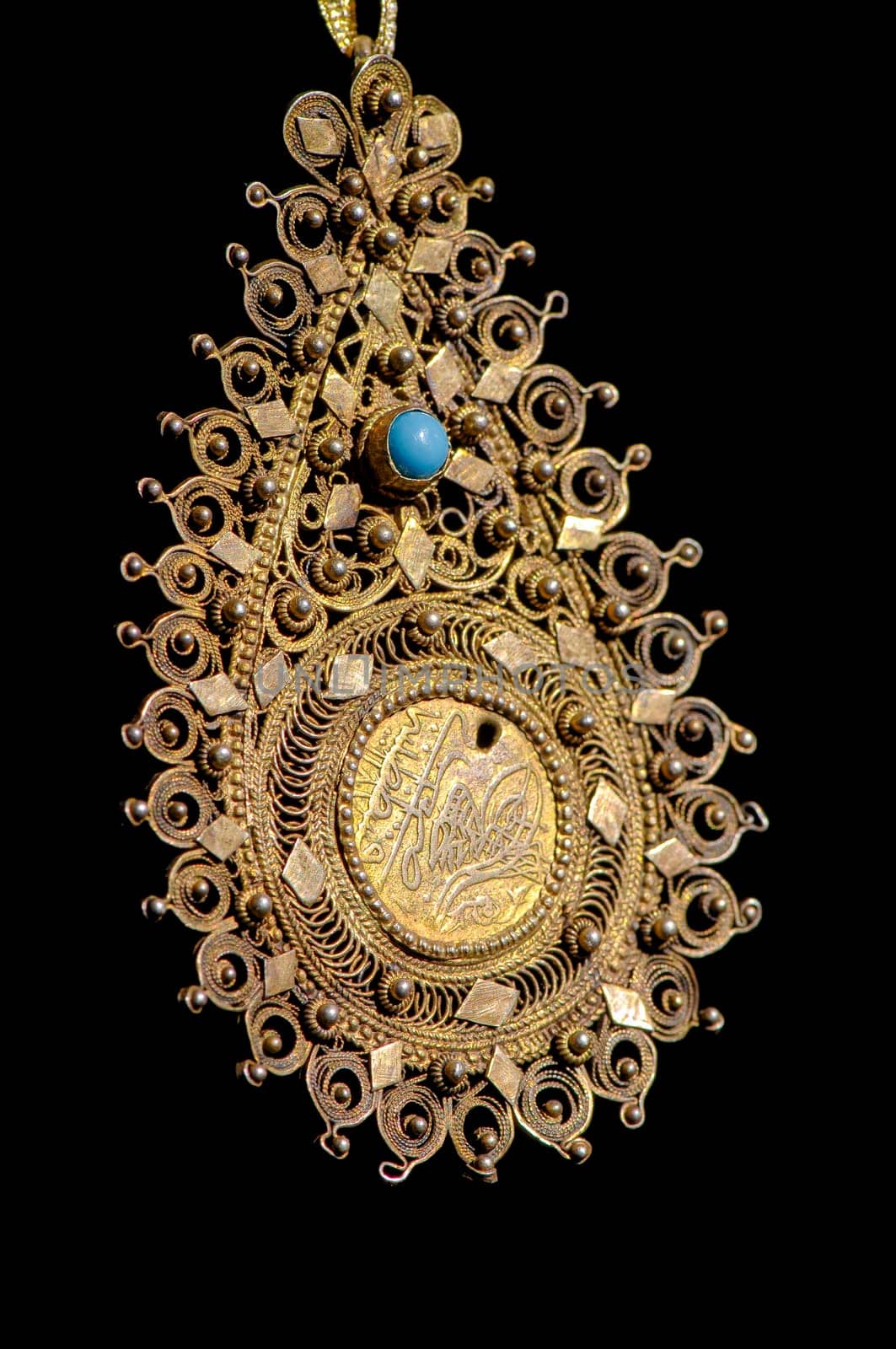 A Vintage, fancy jewelry pendant with precious stones isolated on a black background, vertical
