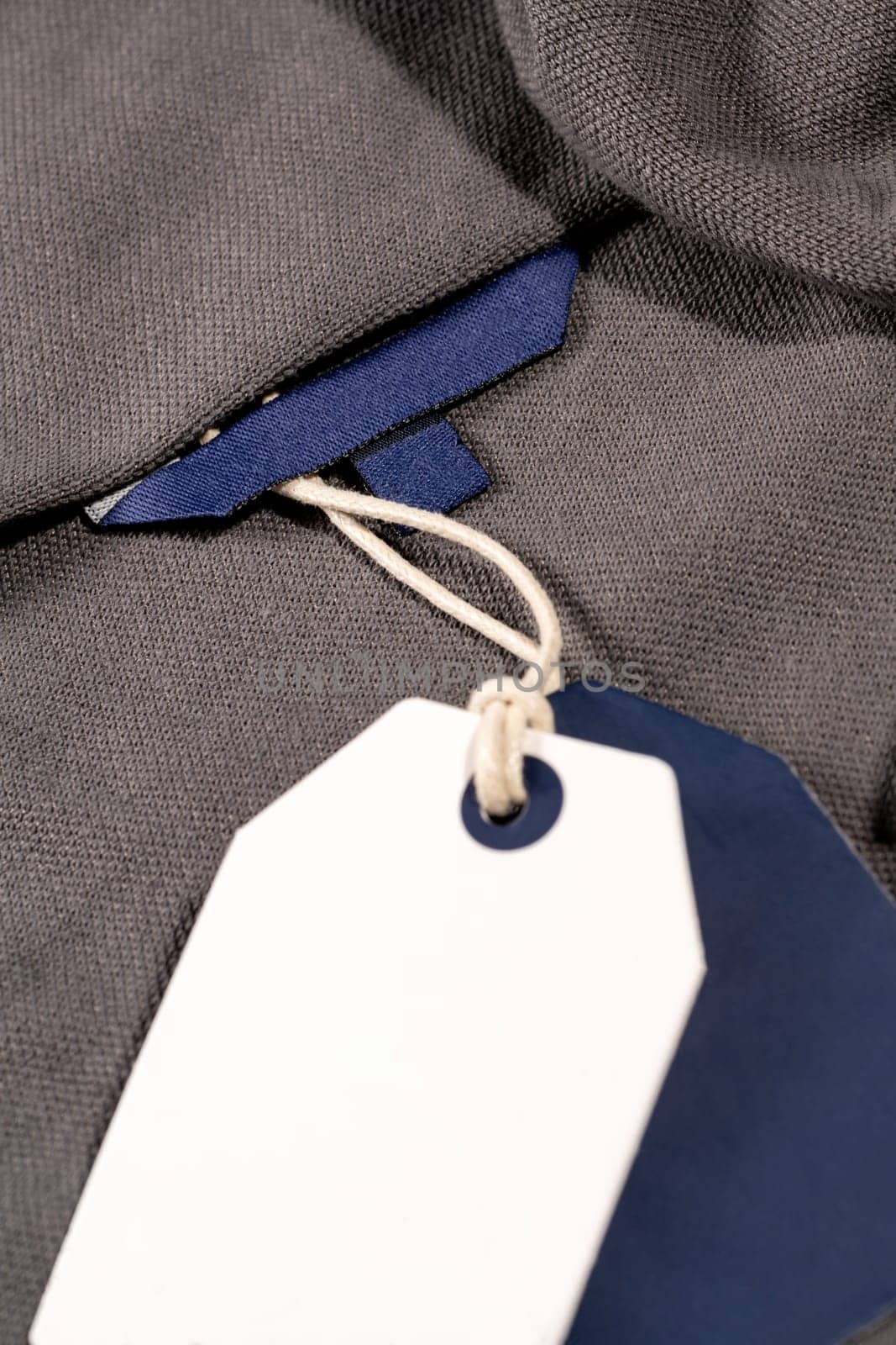 A vertical closeup shot of white blue tags on a string on a cloth with a blank blue tag on the neck