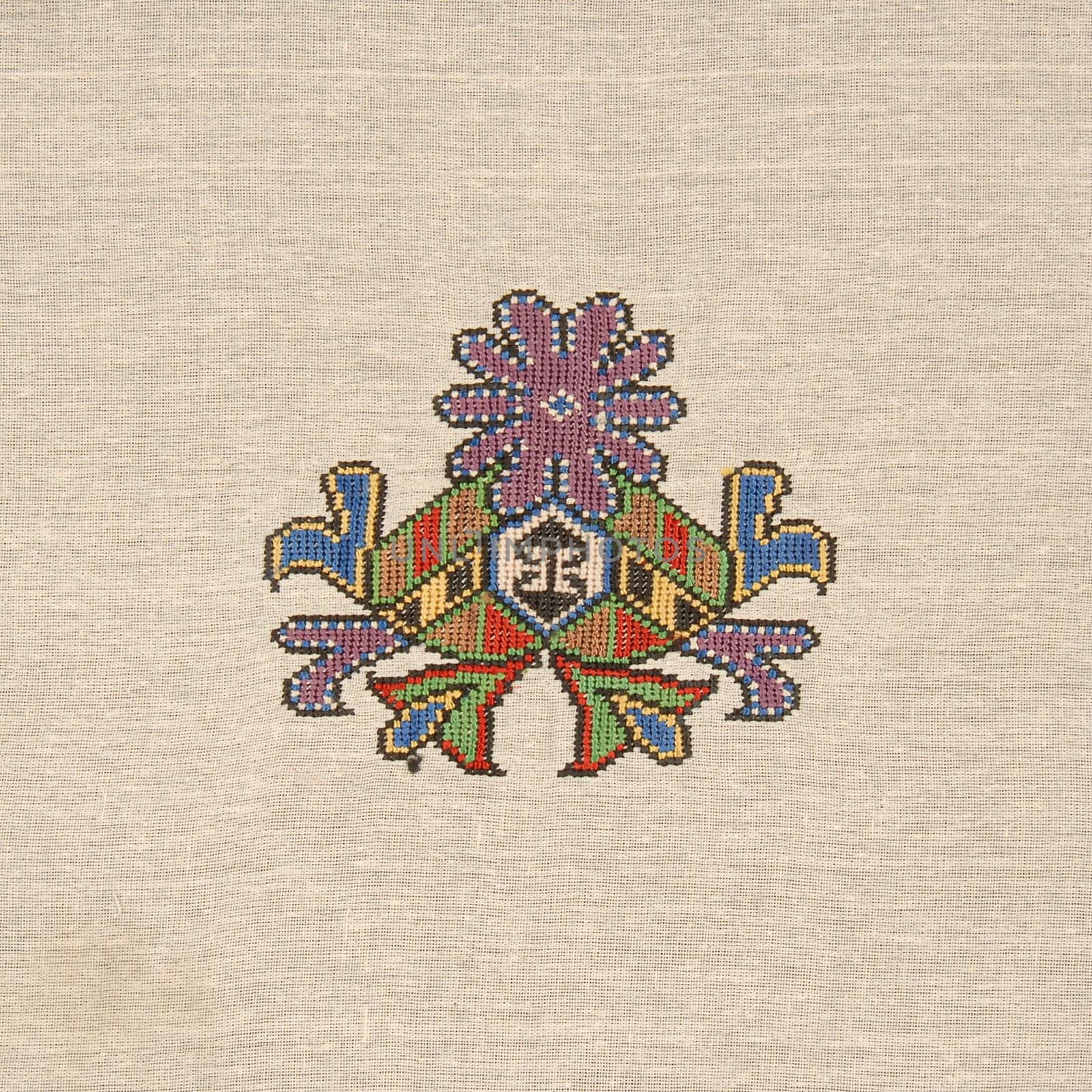 A closeup shot of an abstract colorful embroidery design on a beige cloth by A_Karim