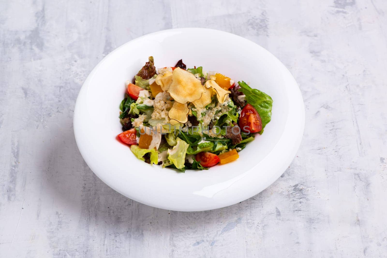 A closeup shot of tasty Caesar salad served in a white dish on white marble surface