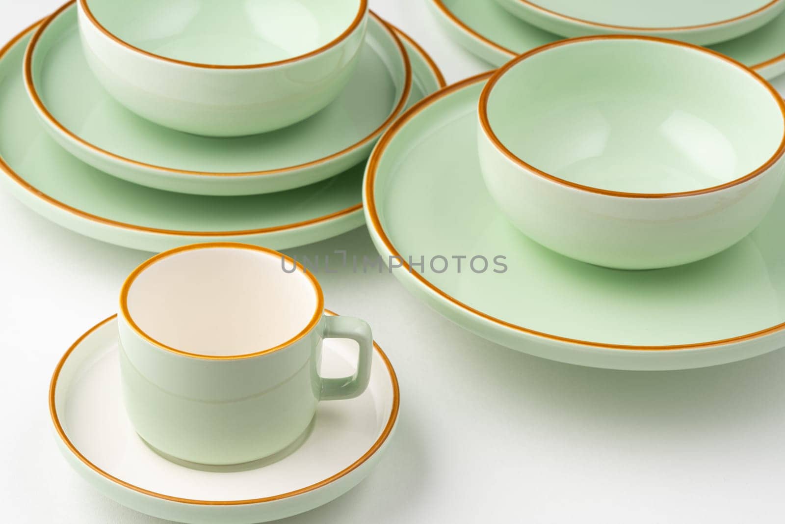 A set of white and pastel green ceramic tableware with orange outlines