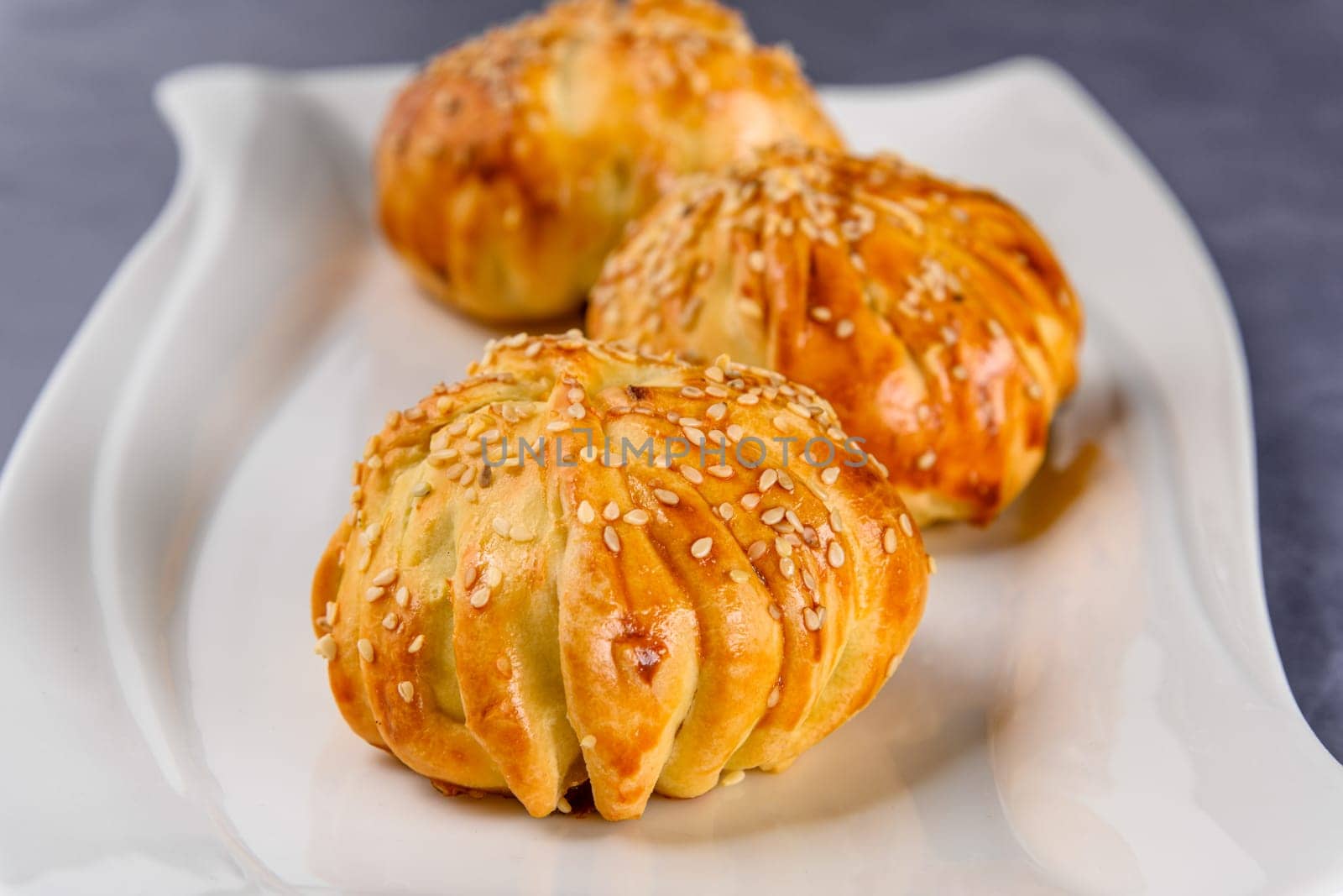 The meatballs wrapped in puff pastry covered with sesame seeds on a white plate