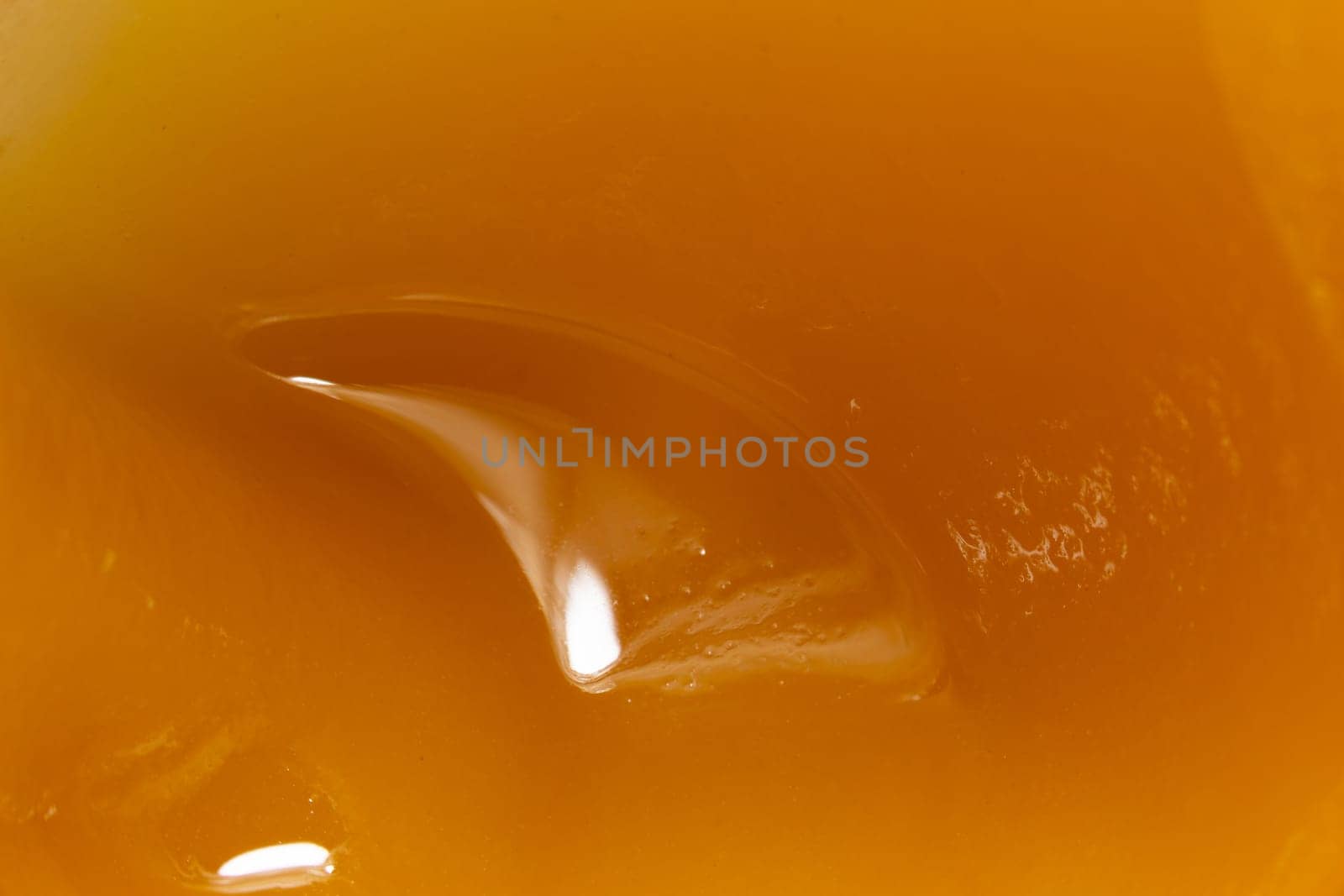 Honey orange textured liquid background, extreme close-up macro view