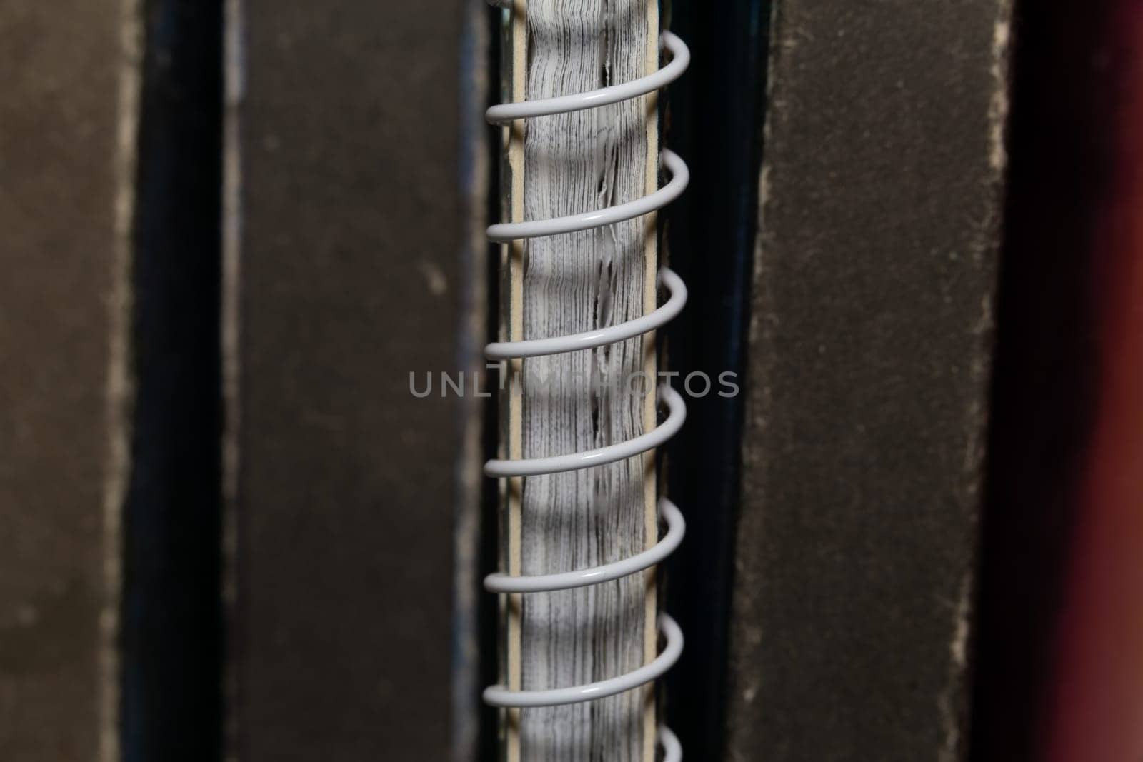 A spring-loaded notebook among old brown book volumes, close-up macro view