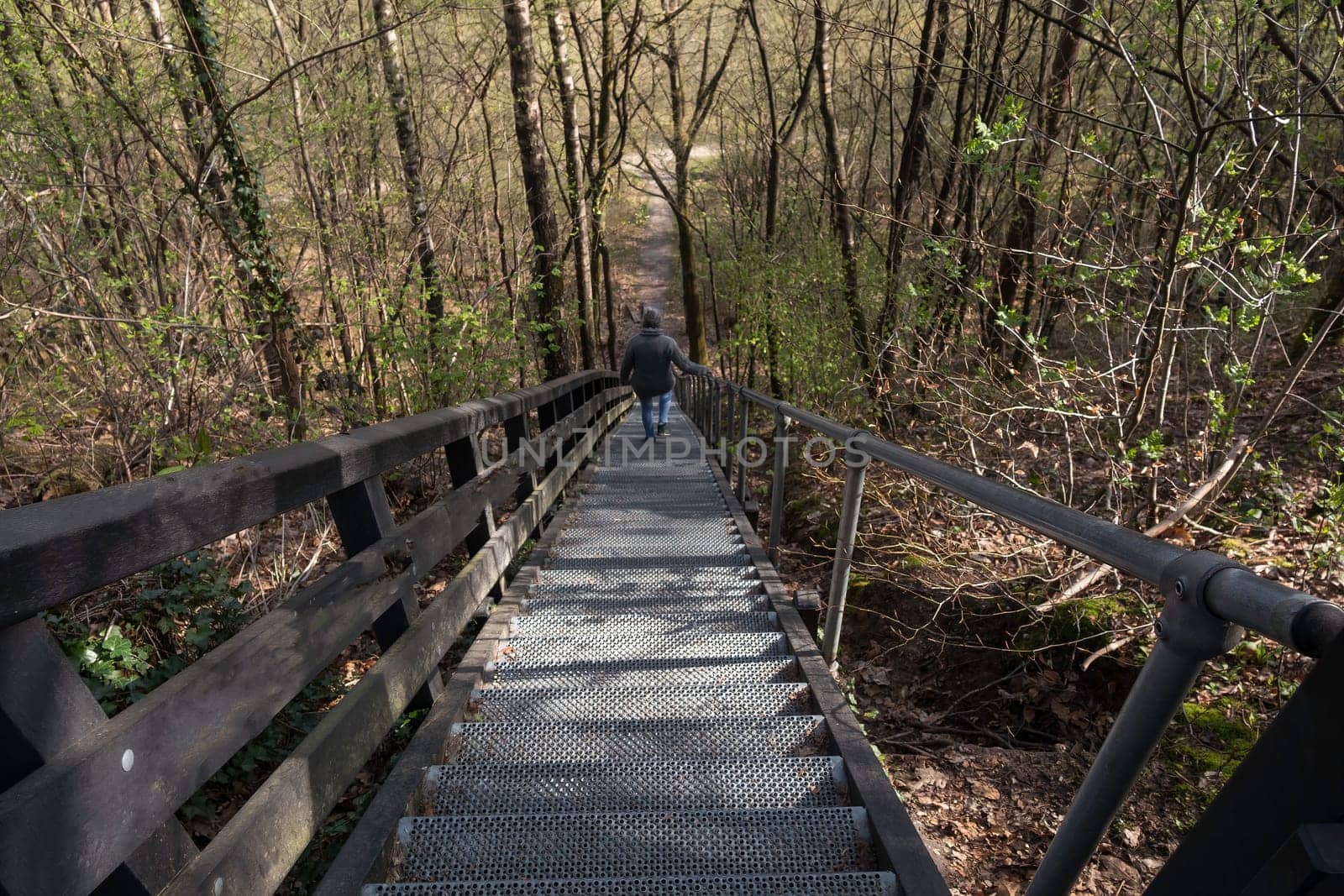 adult woman walks down a large metal staircase in the nature reserve near doorn in the netherlands