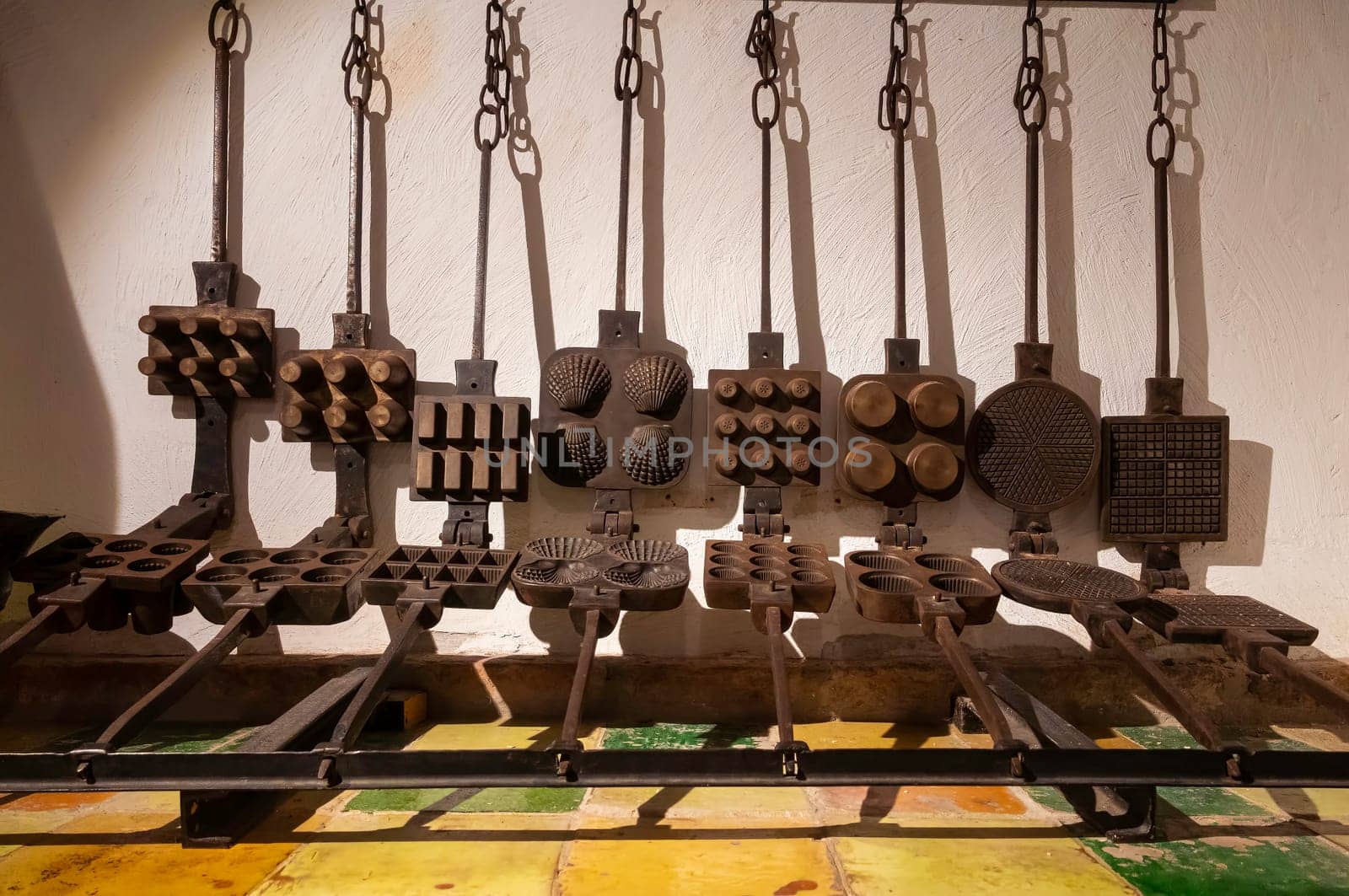 a wall in a bakery full of old metal waffle irons in various shapes such as round shell with and without rims that were formerly used to bake waffles